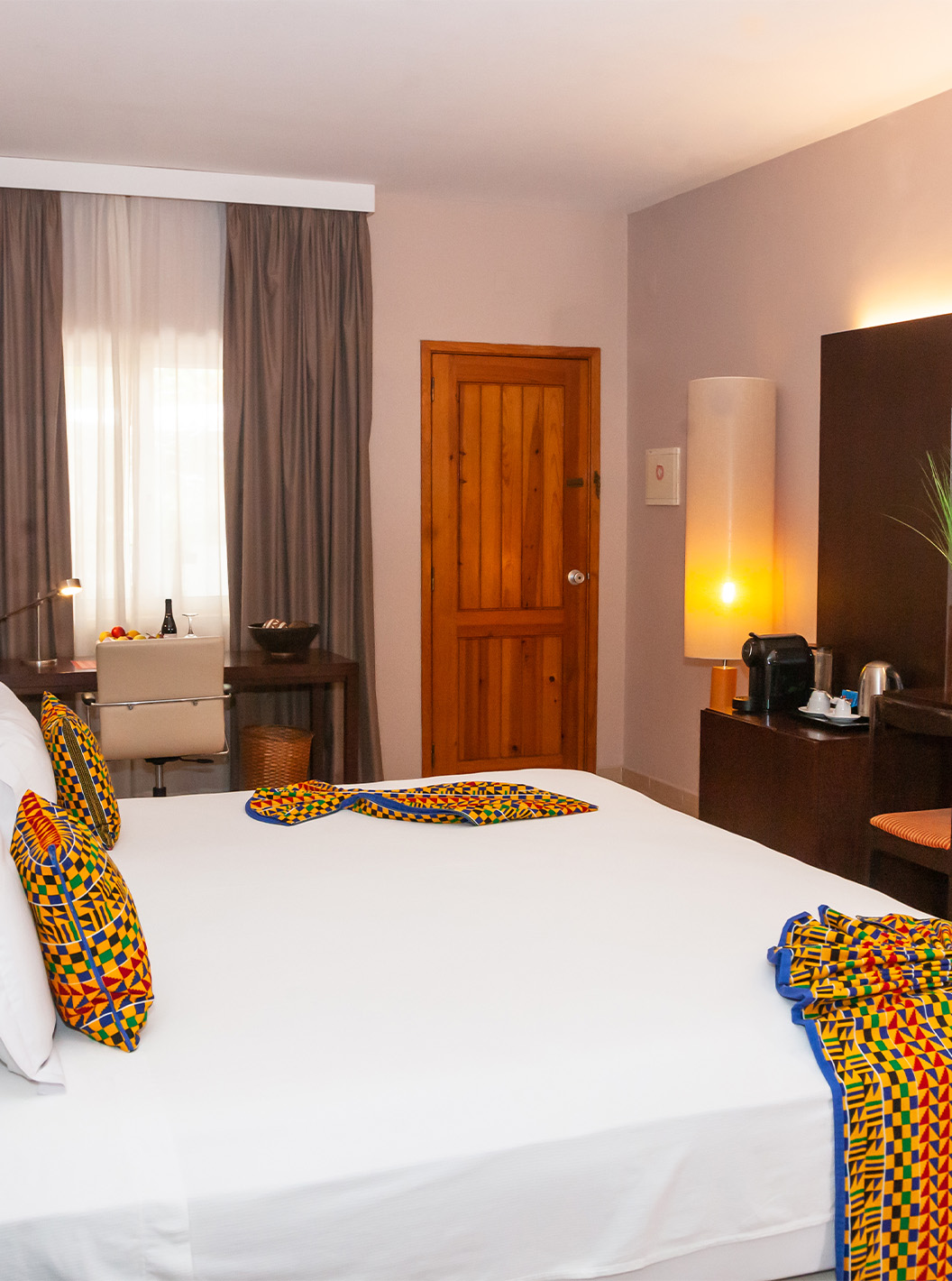 De Junior Suite van Pestana Tropico heeft een tweepersoonsbed, televisie, spiegel en bureau met stoel en fruitmand