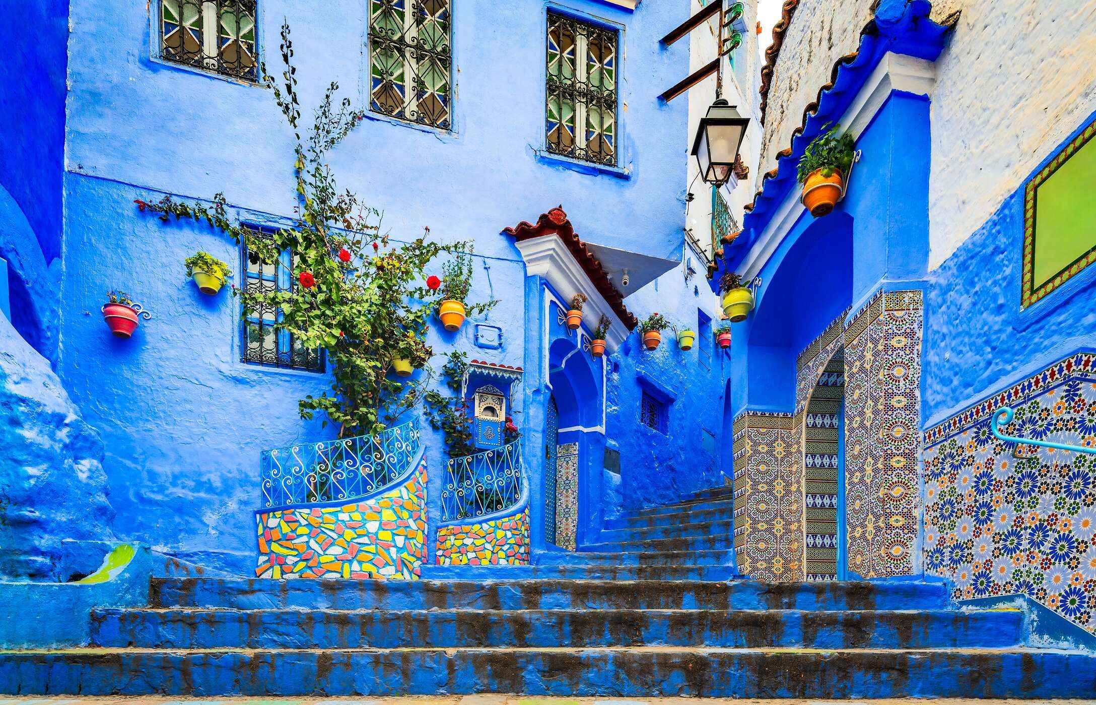 Trap in Chefchaouen, met blauwe gebouwen, betegelde patronen en hangende potten.