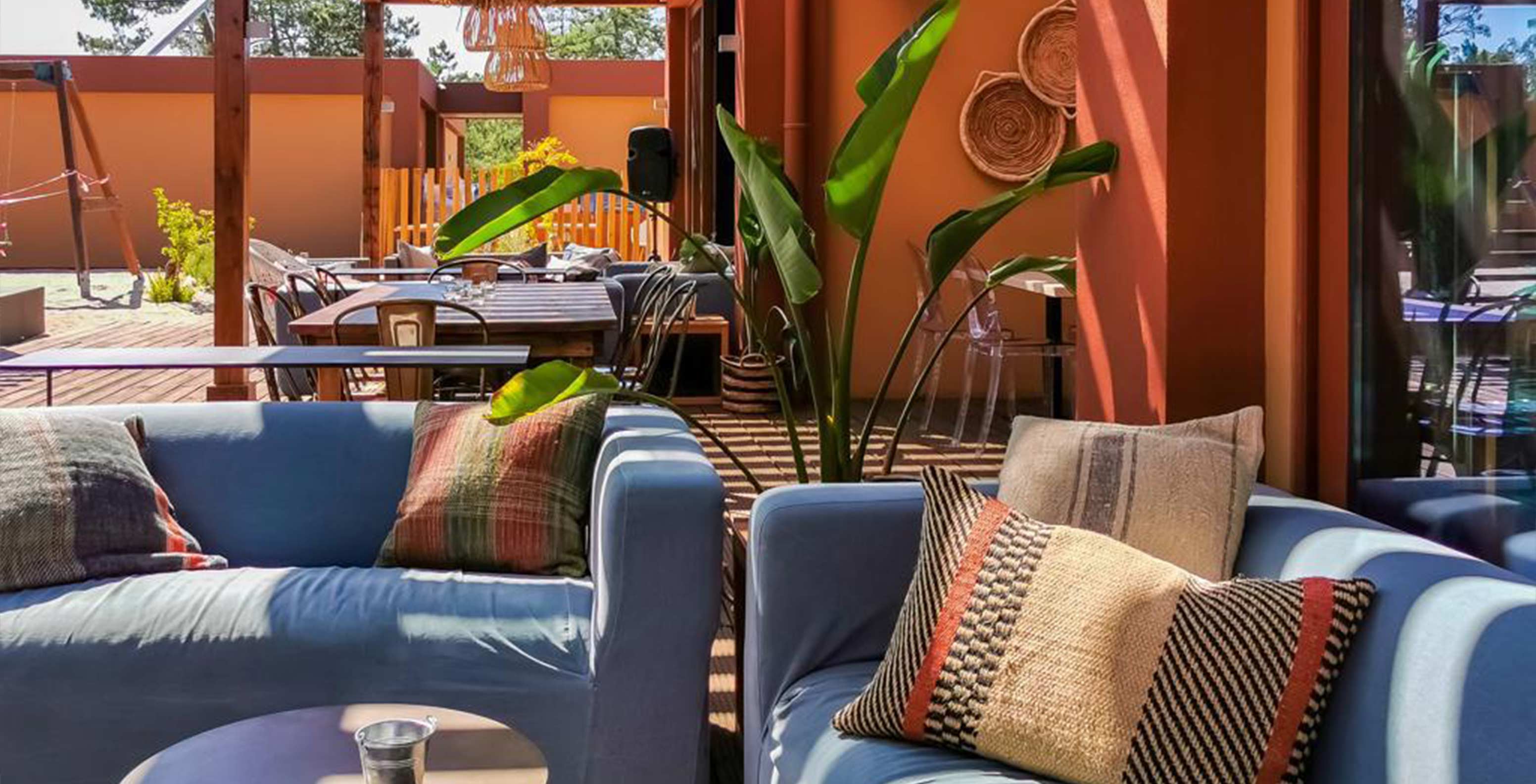 Restaurant Grão de Bico in Pestana Tróia Eco Resort heeft terras met tafels, stoelen en comfortabele sofa’s.