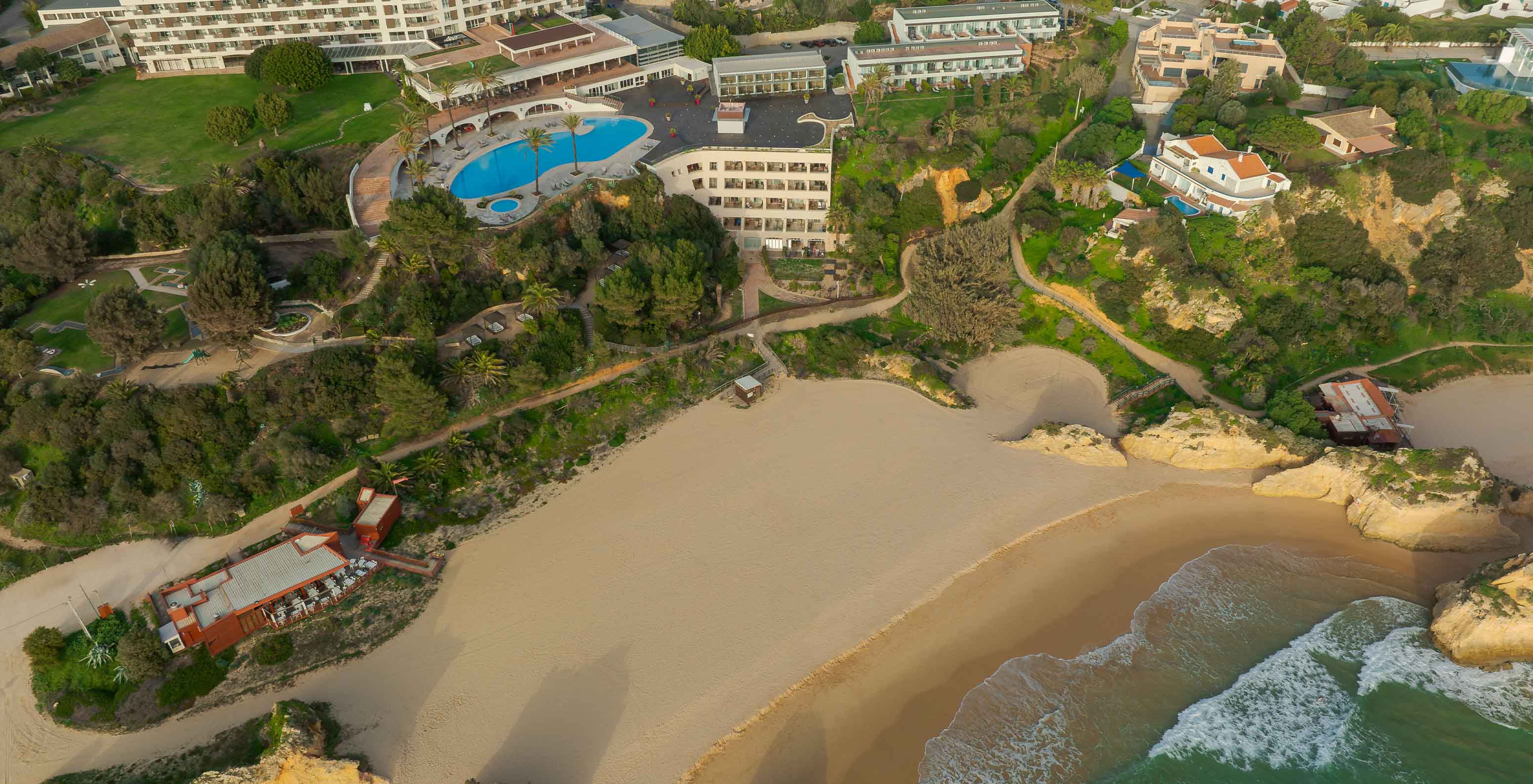 Luchtfoto van hotel Pestana Alvor Praia met het strand van Três Irmãos ervoor, met rotsen, zand en oceaan