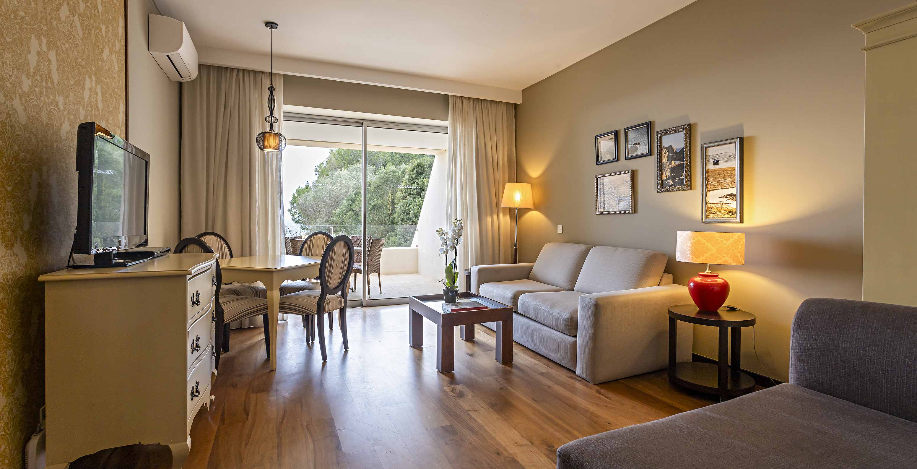 De Cliff Suite T1 in Pestana Alvor Praia heeft een woonkamer met 2 banken, een dressoir met tv, een eettafel en stoelen