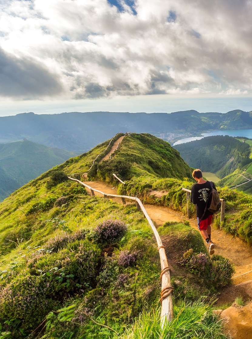 Man loopt op een zandpad met uitzicht op de Lagoa das Sete Cidades, São Miguel Island, Azoren