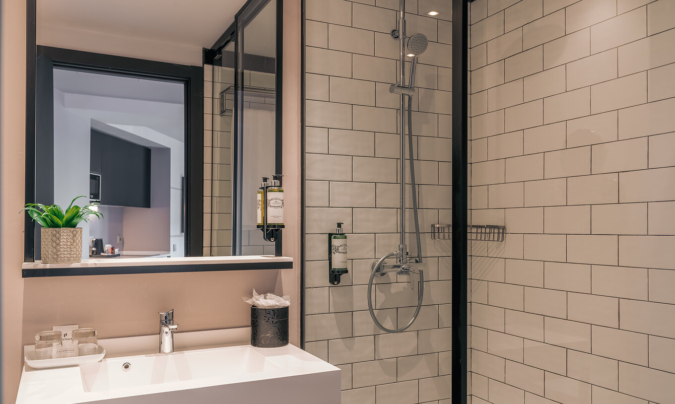 De Double Deluxe Studio Van Pestana Lisboa Vintage Heeft Een Douche Met Glazen Deuren En Zwarte Details En Een Wastafel