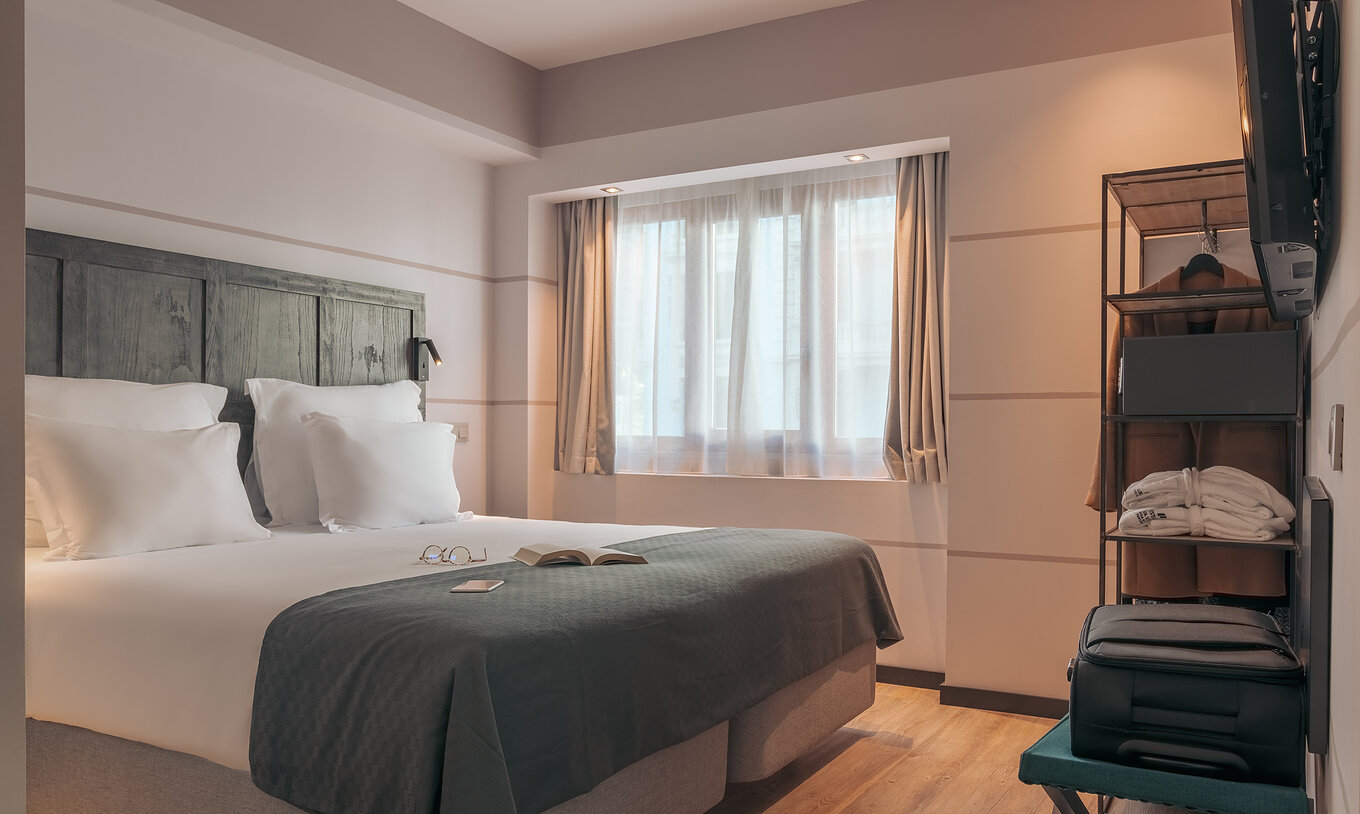 De Double Deluxe Studio Van Pestana Lisboa Vintage Heeft Een Tweepersoonsbed Met Een Grijze Deken En Een Kast Met Een Jas