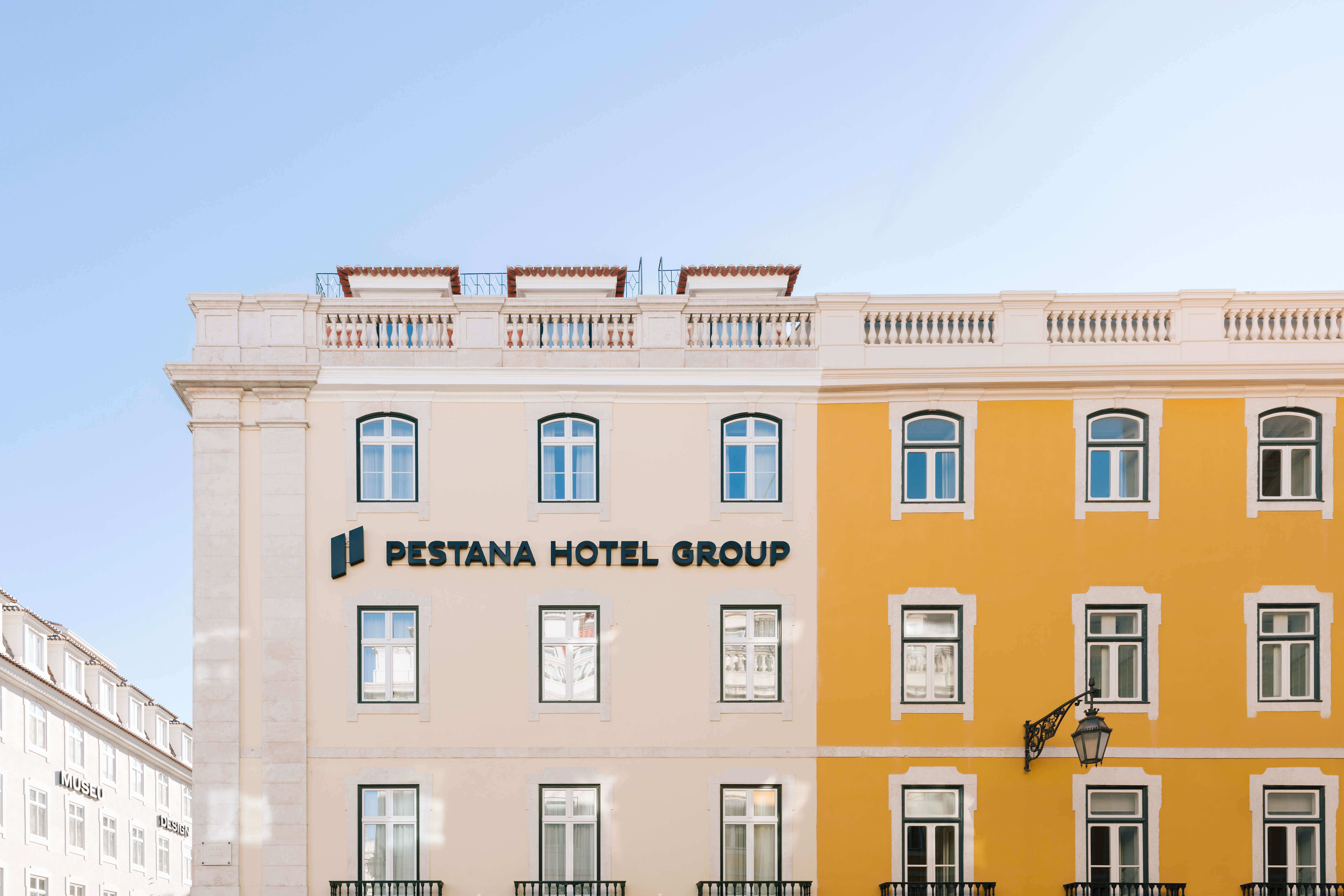 Zijkant van het wit-oranje gebouw van Pestana Rua Augusta Lisboa met logo van Pestana Hotel Group