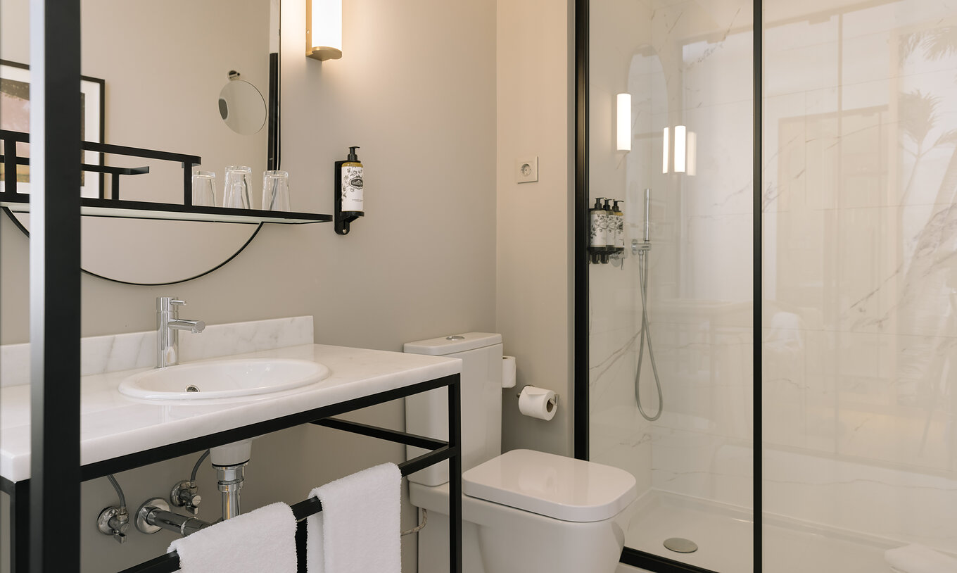 De Premium Corner Kamer van Pestana Rua Augusta Lisboa heeft badkamer met wastafel met spiegel, handdoeken, toilet en douche
