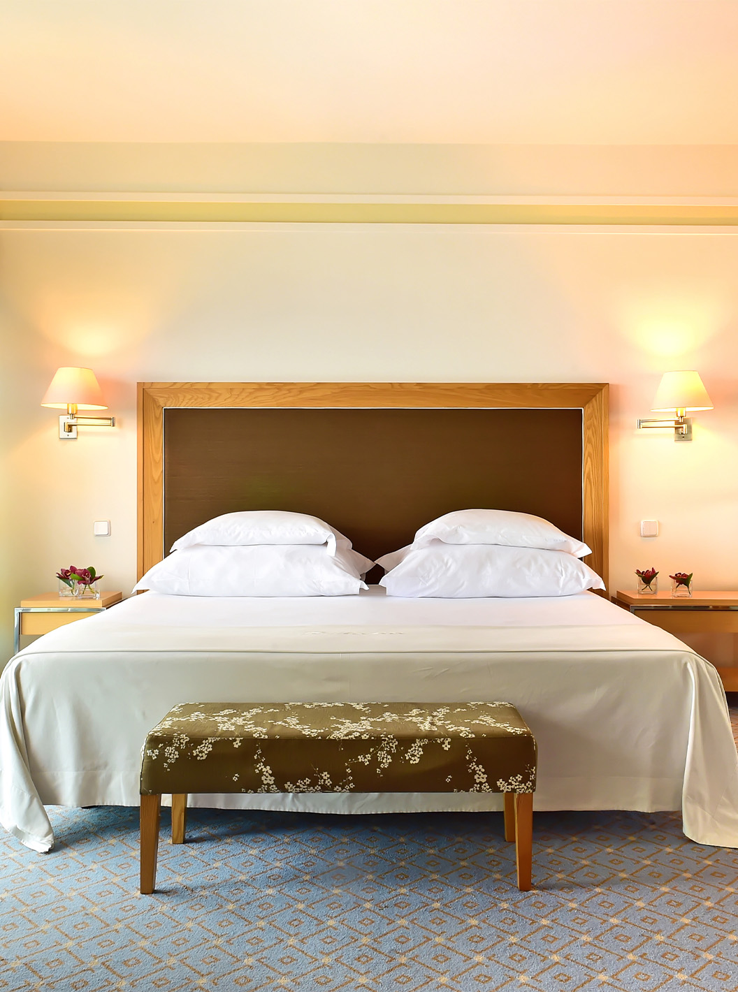 De Junior Suite van Pestana Carlton Madeira heeft een tweepersoonsbed met een bank aan de voet en een kast met spiegels