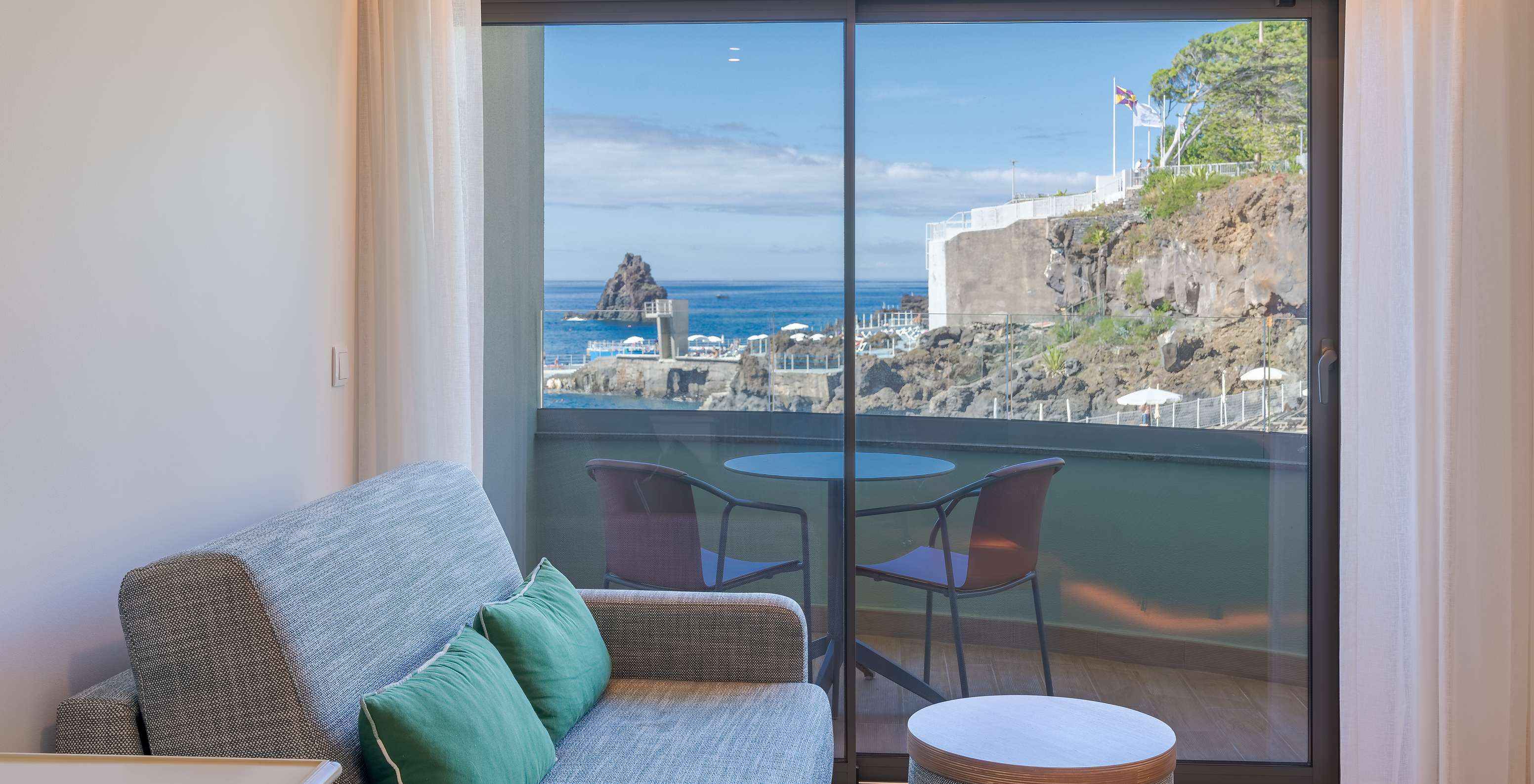 De Classic Sea View Side kamer van Pestana Vila Lido Madeira heeft een bank naast het balkon met zijdelings zeezicht