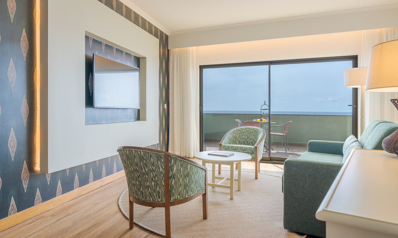 De Suite Superior Sea View van Pestana Vila Lido Madeira heeft een woonkamer met bank, fauteuils en televisie