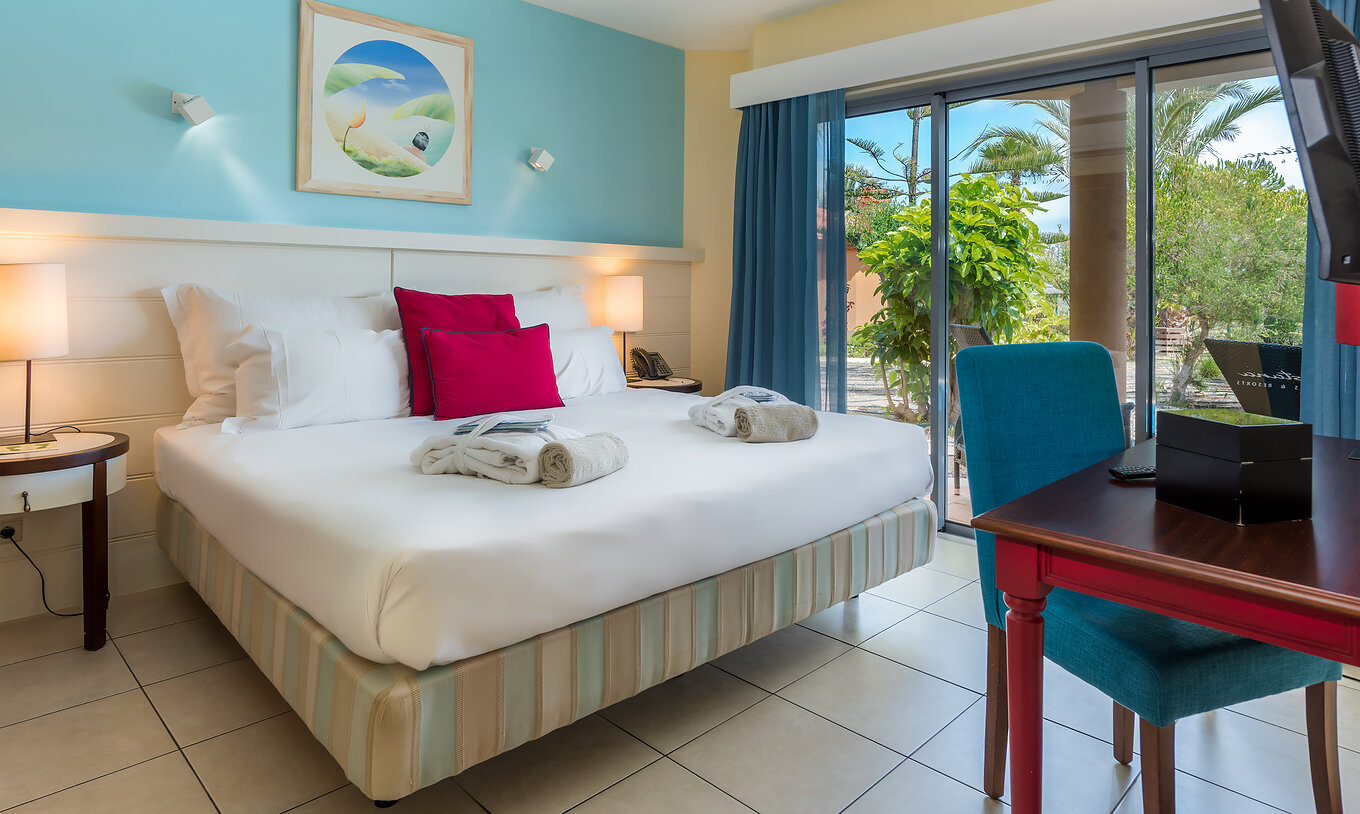 De Pool Villa van Pestana Porto Santo All Inclusive heeft een slaapkamer met tweepersoonsbed en een groot raam in blauwtinten