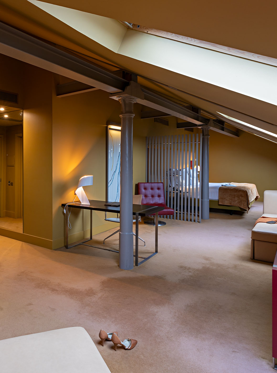 De Loft Attic van Pestana Palácio do Freixo beschikt over een beige leren bank, een bureau en een rode kast