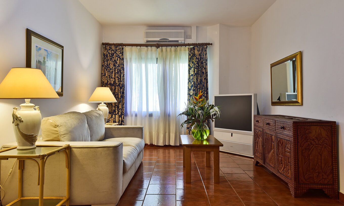 De Suite Van Pestana Miramar São Tomé Heeft Een Woonkamer Met Bank Televisie En Een Tafel Met Een Vaasje Bloemen