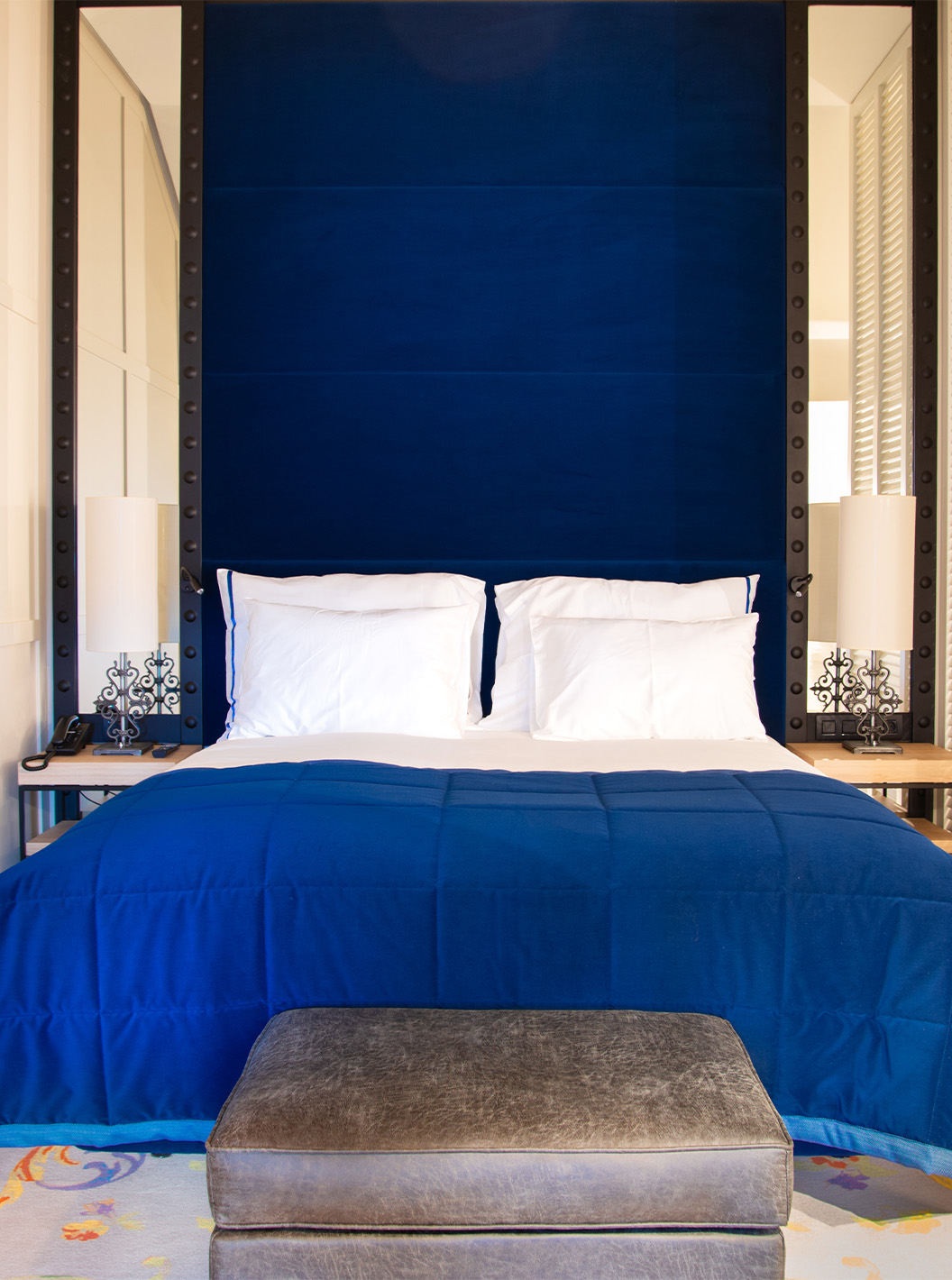 De Loft van Pestana Plaza Mayor Madrid heeft een tweepersoonsbed met een blauwe hoofdeind en spiegels en een tv aan de muur