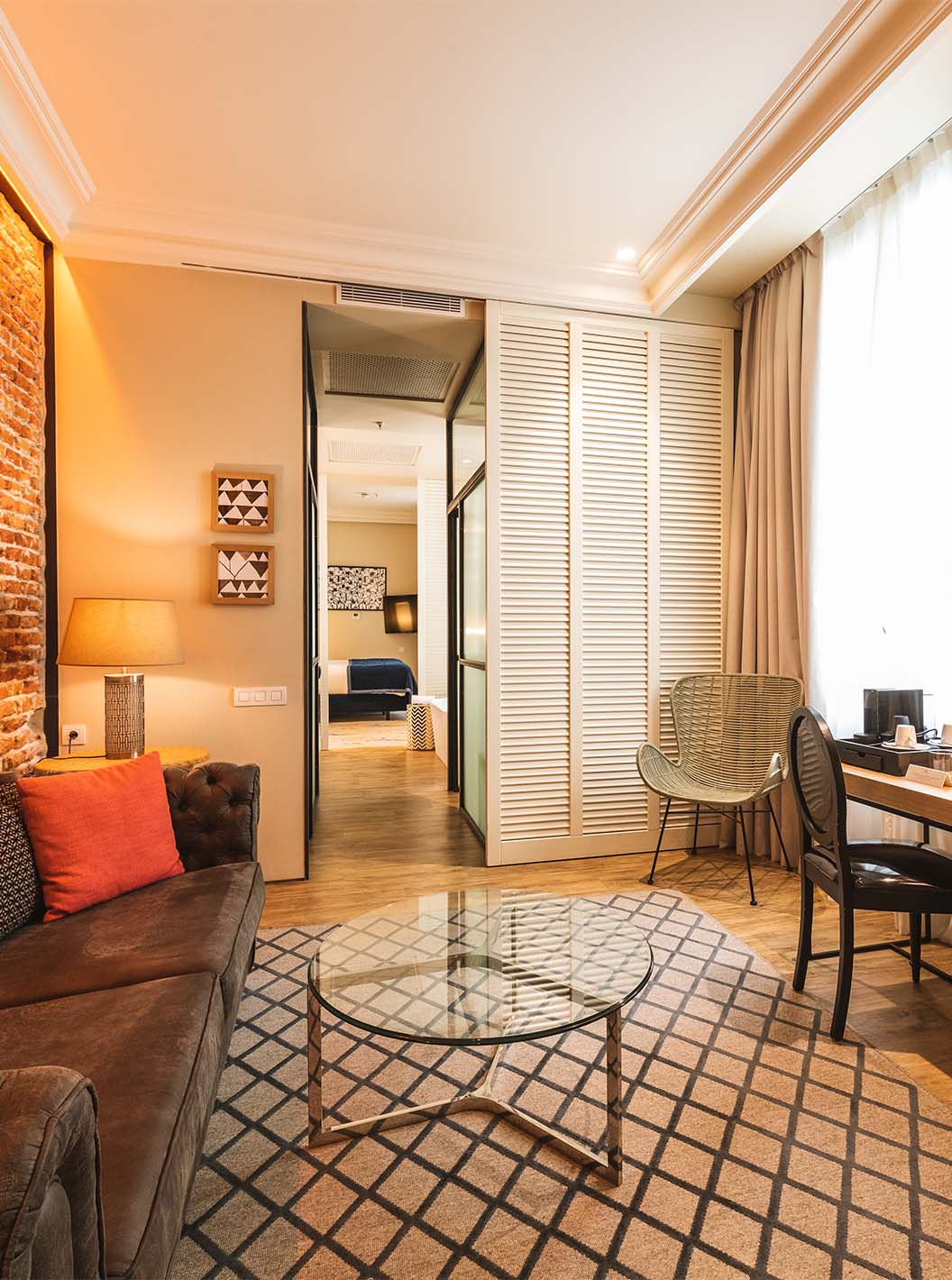 De Suite van Pestana Plaza Mayor Madrid heeft een woonkamer met bureau bank tv en een bakstenen muur