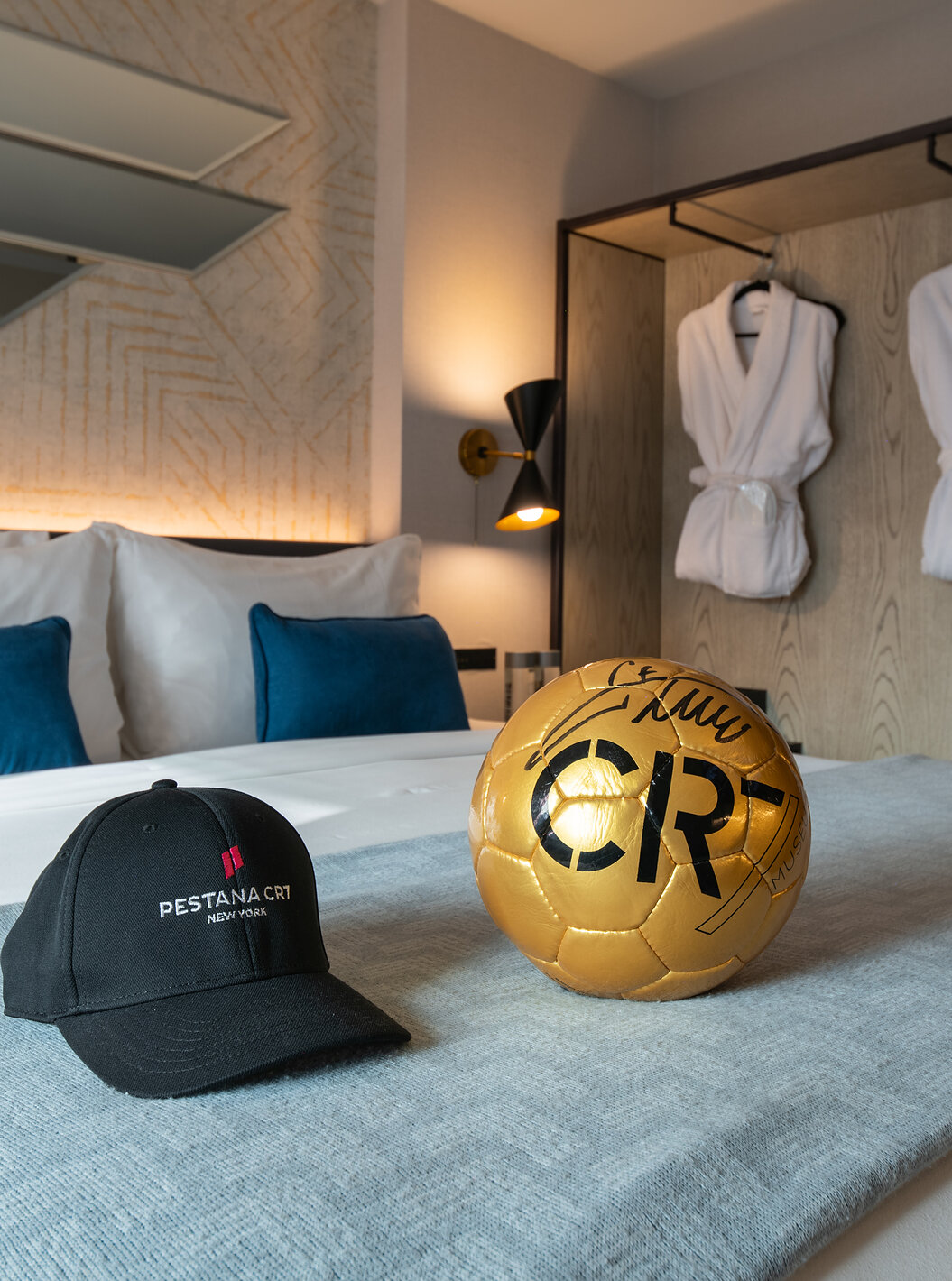 De Deluxe King Room van Pestana CR7 Times Square heeft een tweepersoonsbed met een CR7-bal en hoed