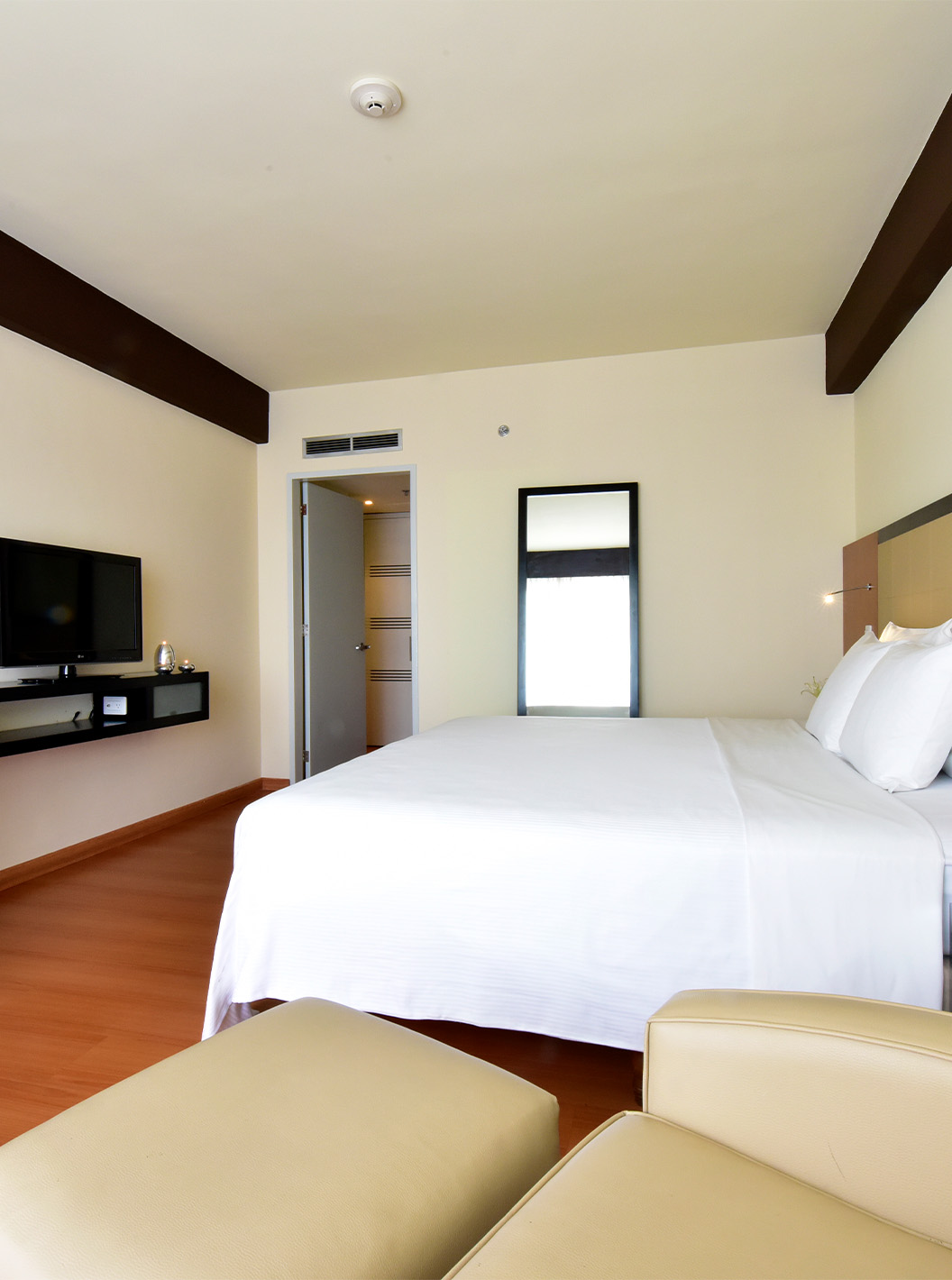 De Twin Superior van Pestana Caracas heeft een tweepersoonsbed, spiegel, bureau en een fauteuil