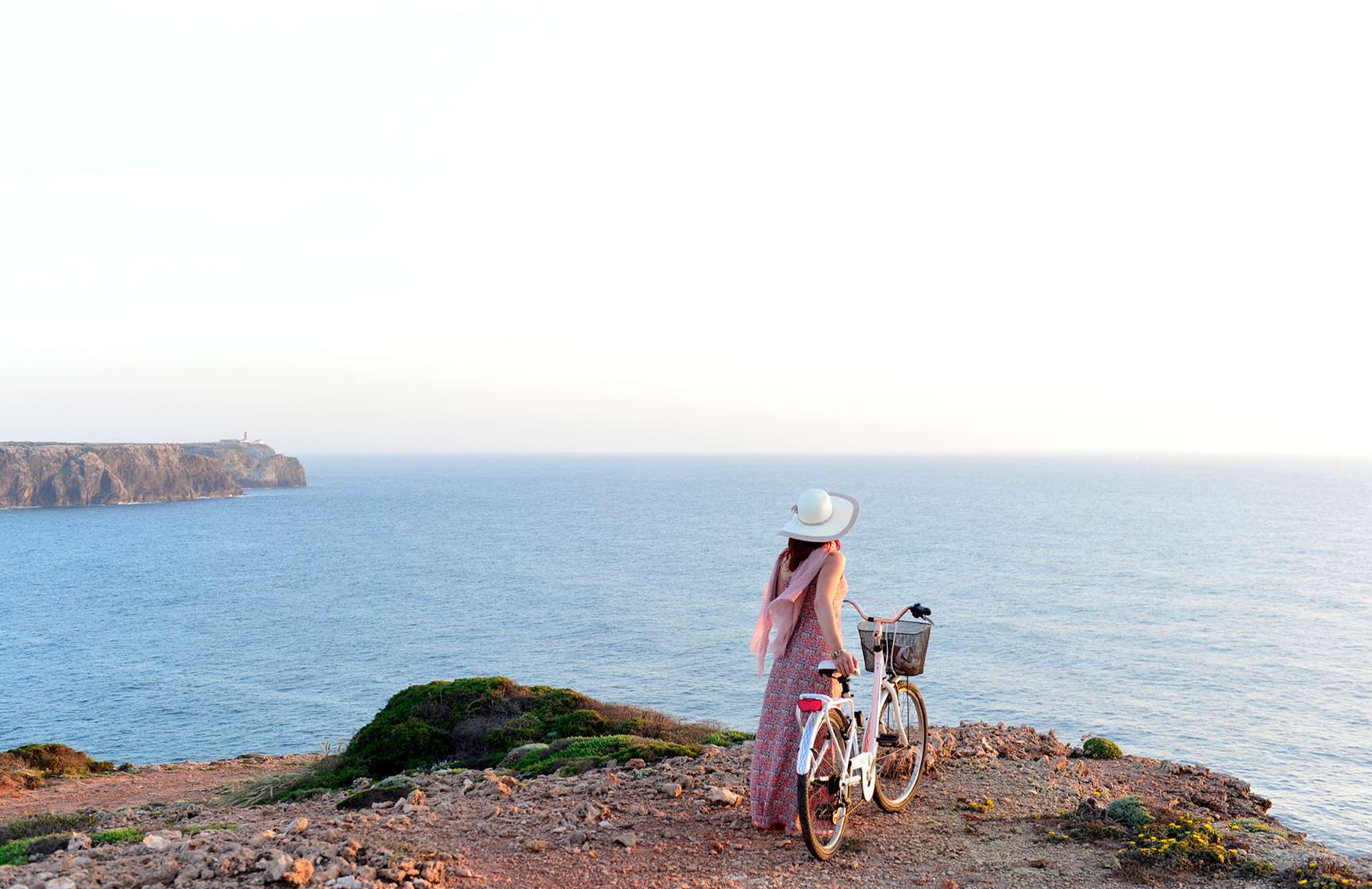 Vrouw loopt met een fiets in de hand langs de kliffen aan de Portugese kust, aangeboden door Pousadas de Portugal