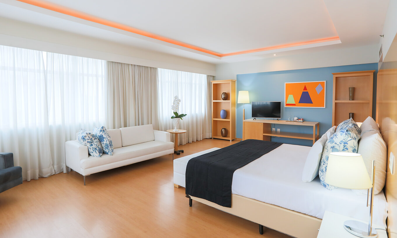 A Suite Executiva do Pestana Curitiba é um quarto amplo com várias janelas, bastante luminoso, com cama de casal e sofá