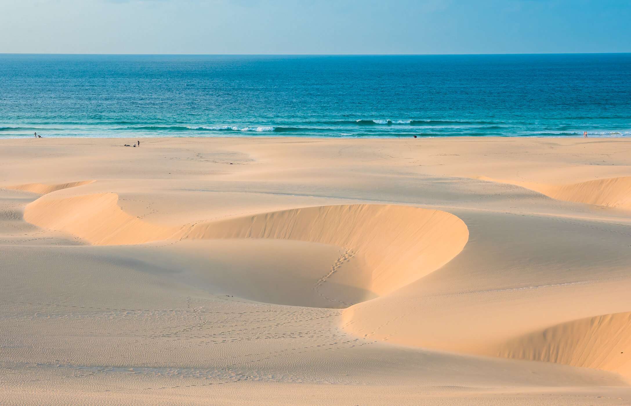 Vista panorâmica da praia de Chaves, com dunas de areia esculpidas pelo vento, em contraste com o mar azul turquesa