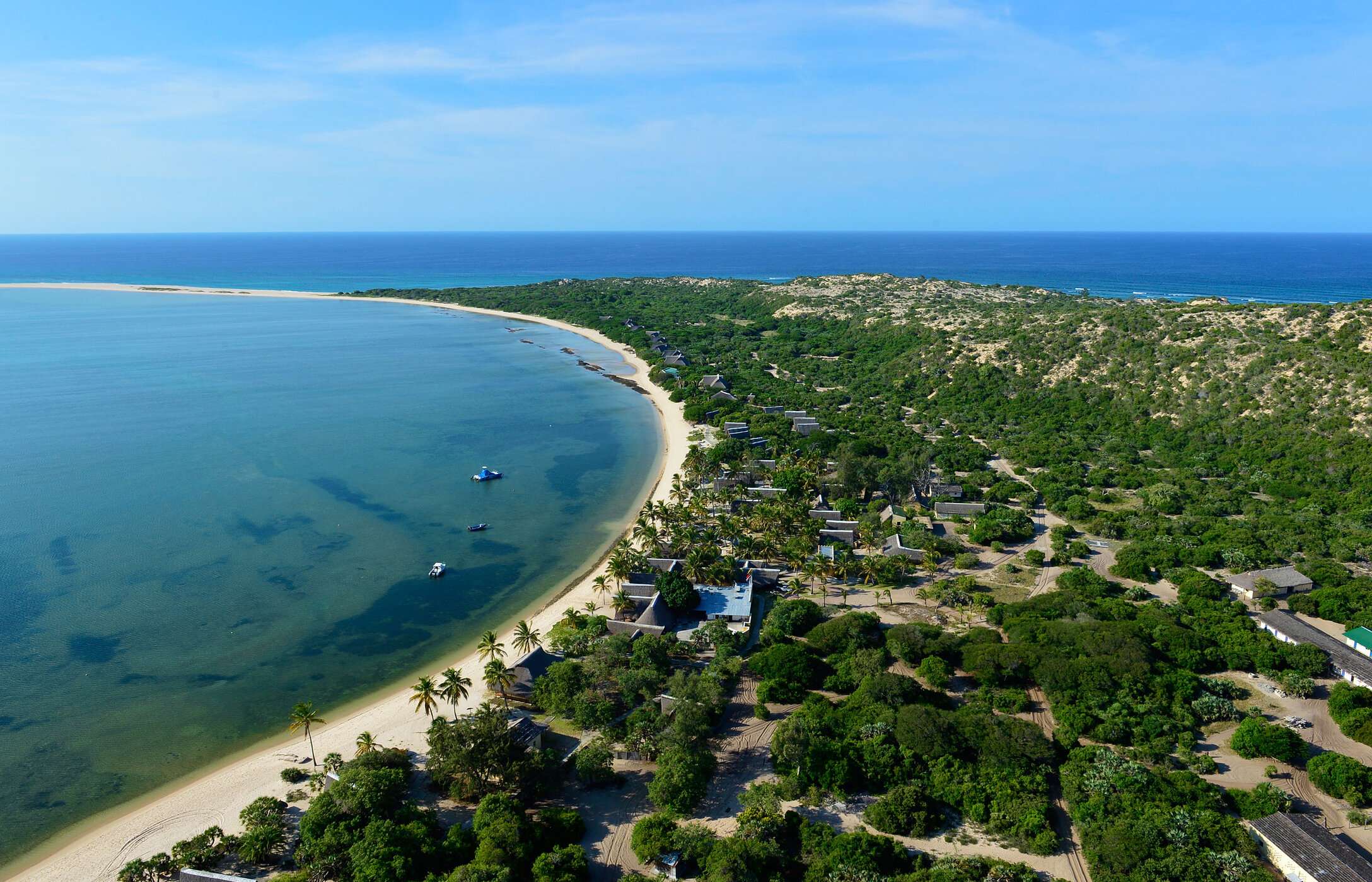 Vista aérea da ilha de Bazaruto em Moçambique, com uma praia de areia branca, rodeada por vegetação e alguns edifícios