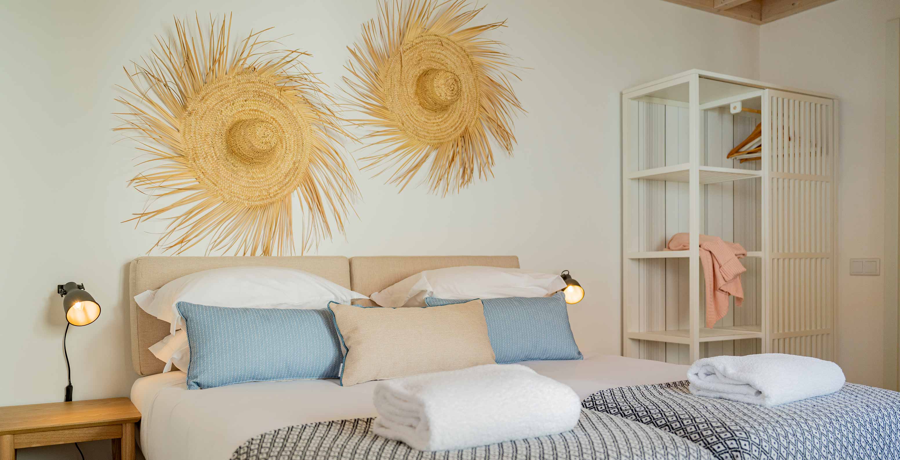 A Superior Villa do Pestana Comporta Village Residences tem uma cama de casal com decoração de palha na parede