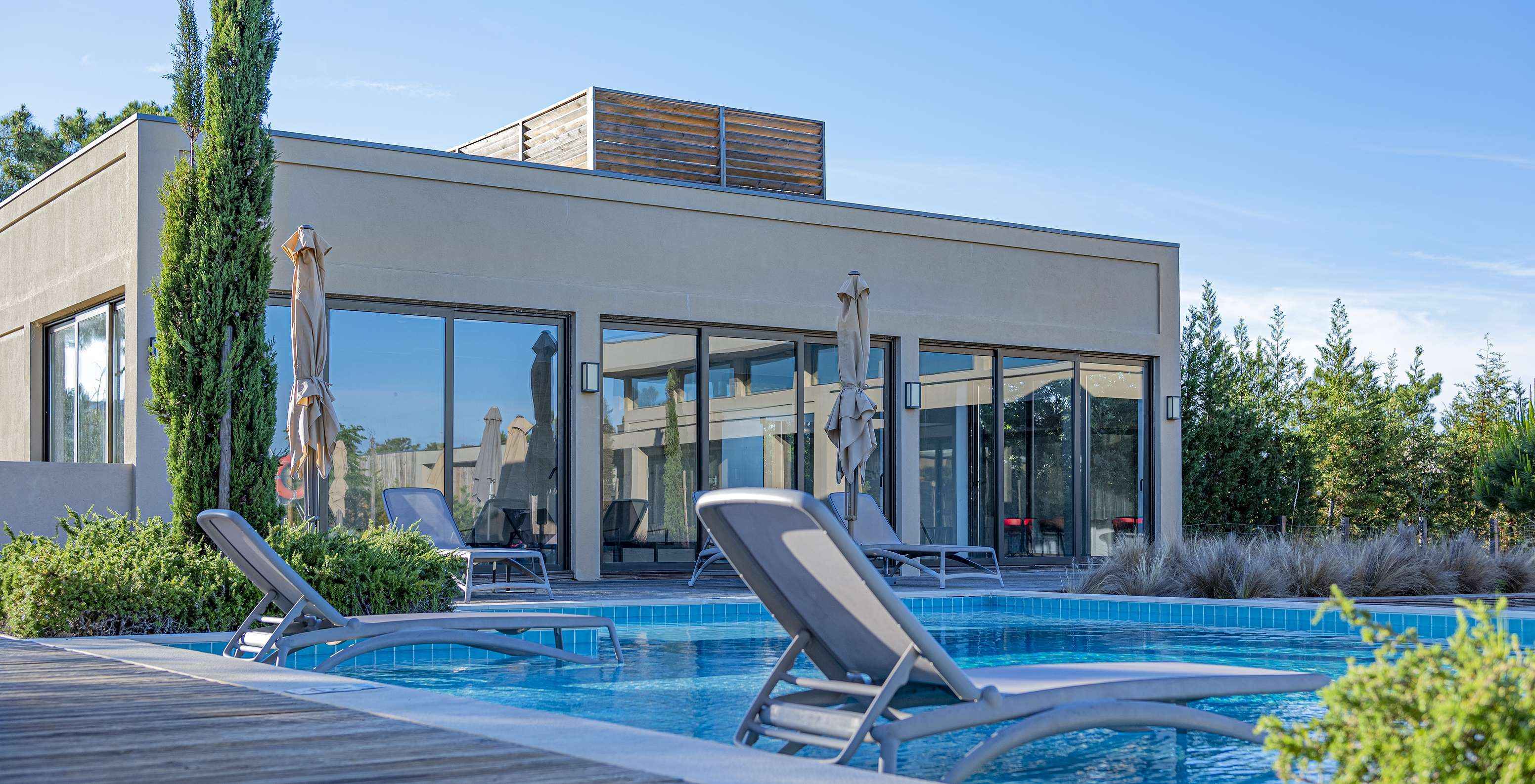 Piscina exterior no Pestana Tróia Eco Resort com duas espreguiçadeiras dentro de água, onde pode descansar