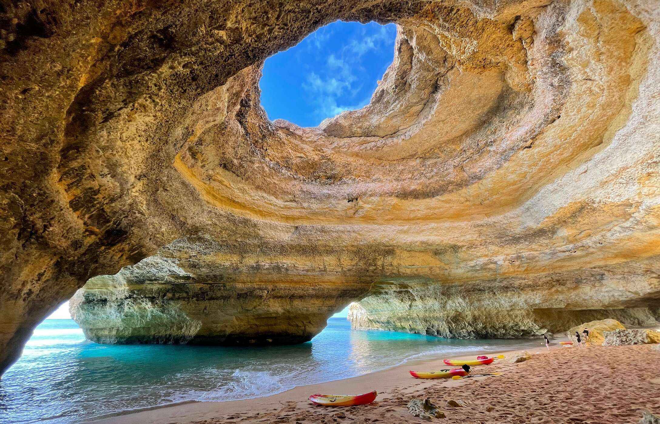 Vista interior da Gruta de Benagil, no Algarve, com uma abertura no teto que permite a entrada de luz natural
