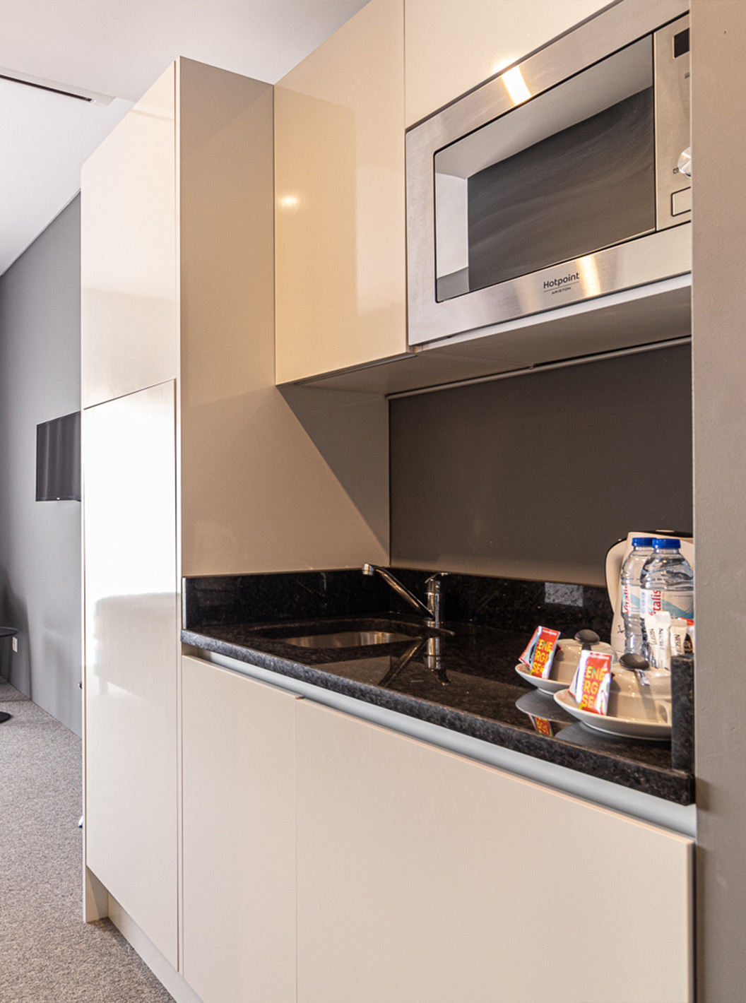 O Quarto Clássico - Vista Piscina do Pestana Gramacho Residences é um quarto moderno com cama, TV e cozinha compacta.