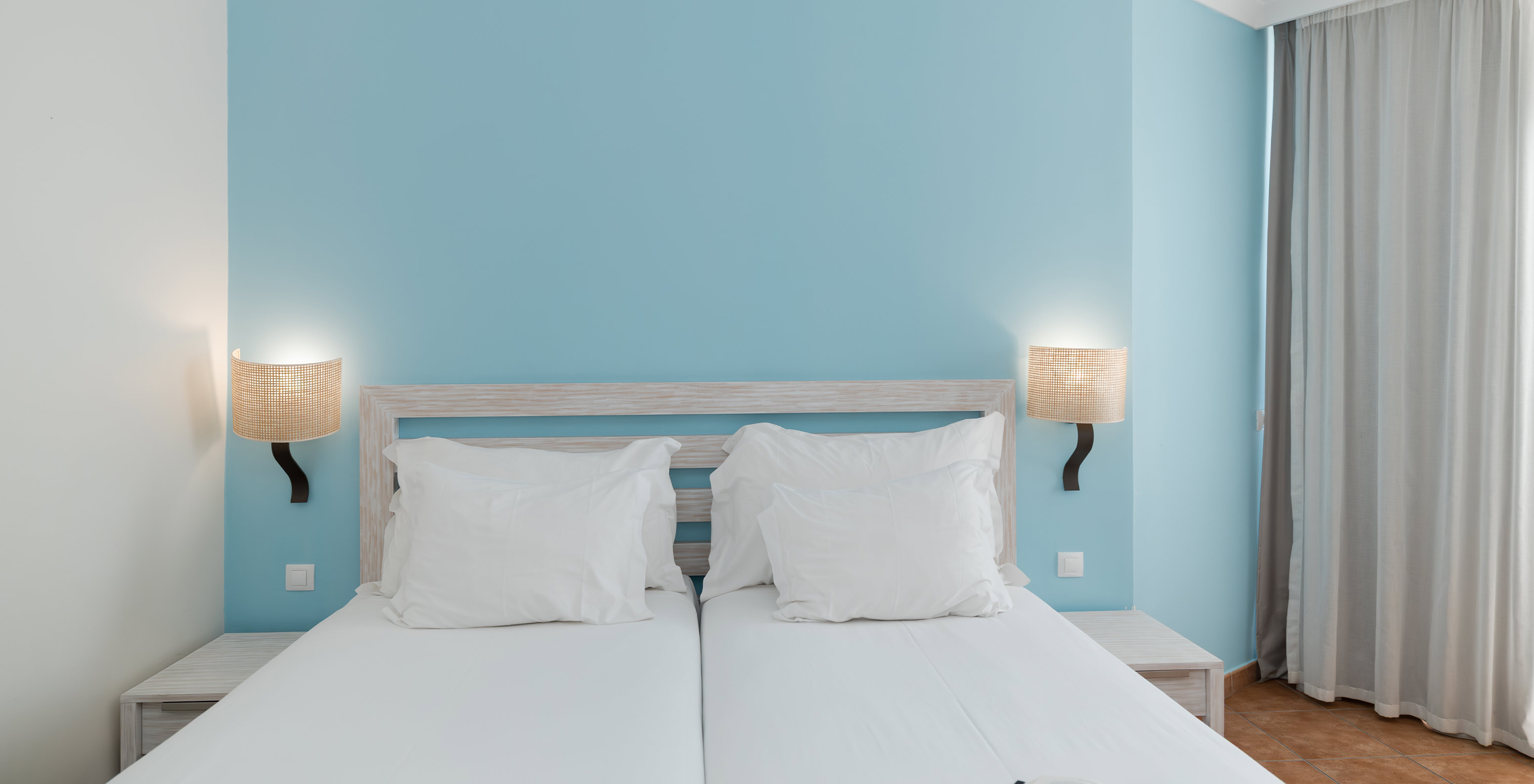 O Deluxe Vista Jardim do Pestana Viking tem duas camas individuais com duas mesas de cabeceira e papel de parede azul