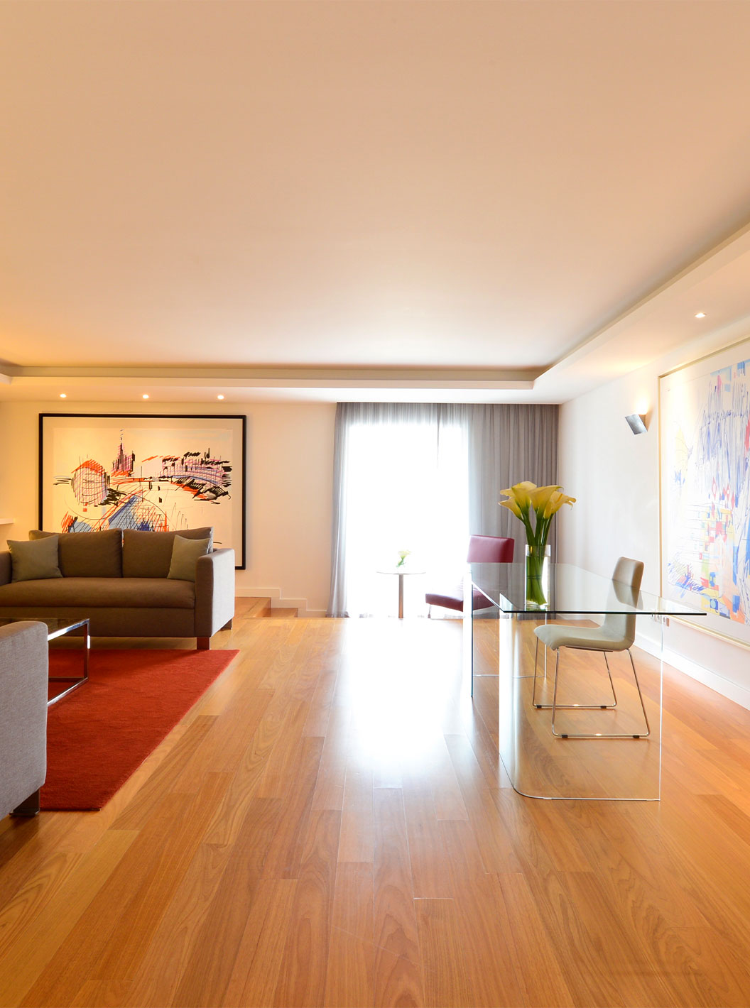 A Suite Presidencial do Pestana Cidadela Cascais tem uma sala com uma secretária transparente e cadeira, quadros e um sofá