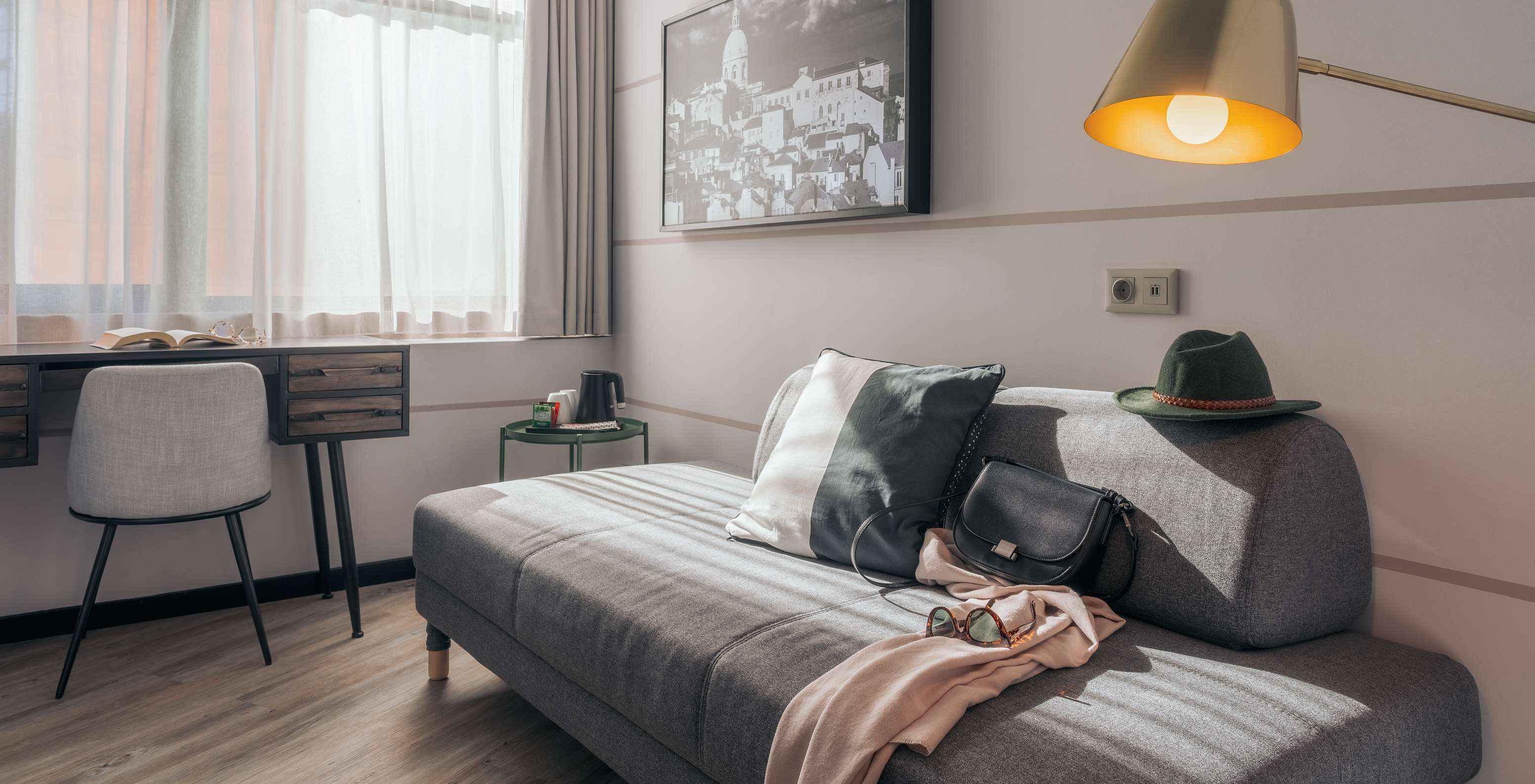 O Double Superior do Pestana Lisboa Vintage tem um sofá cinzento, uma secretária com cadeira, uma mesa de apoio e um quadro