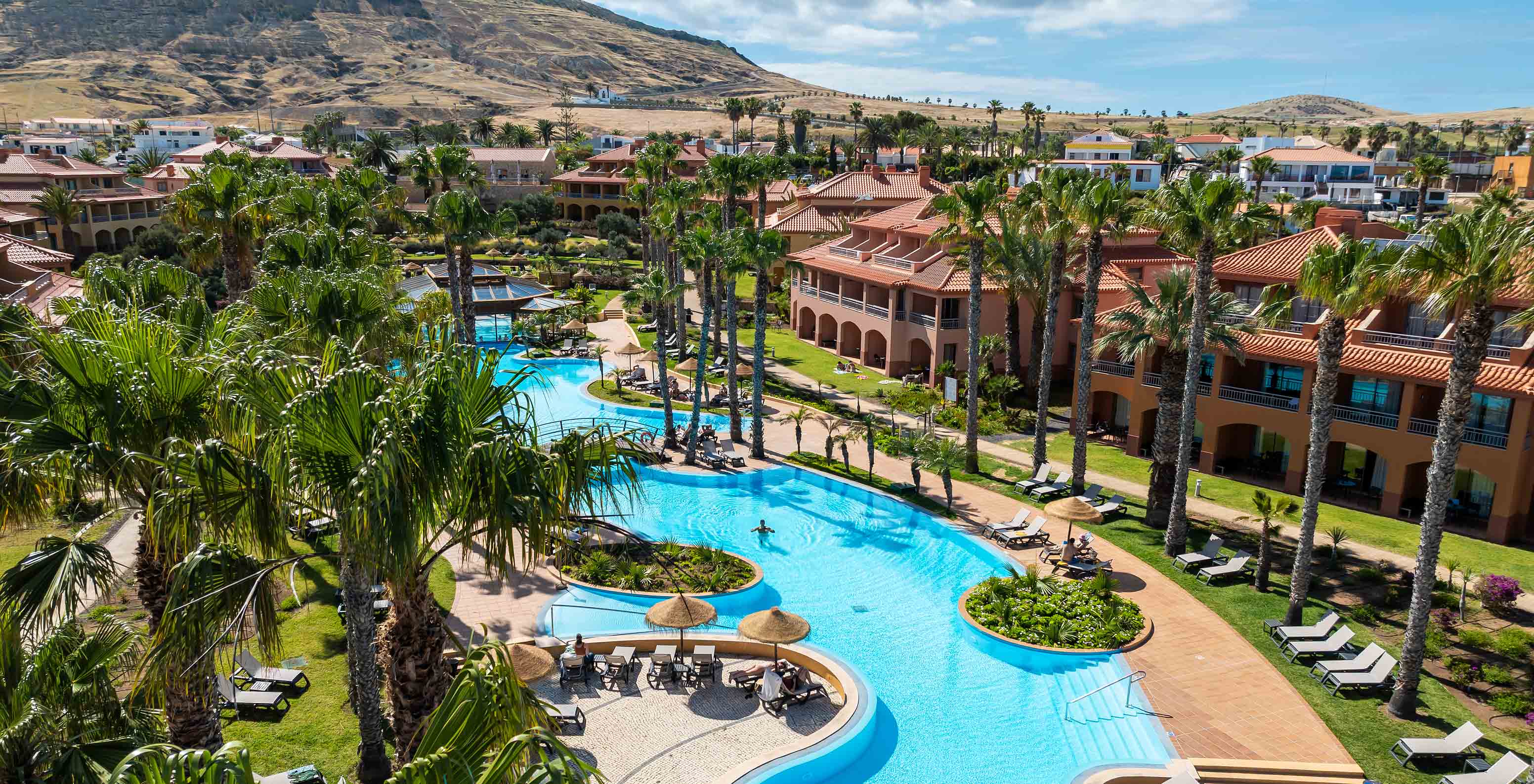 Disposição das vilas do Pestana Porto Santo All Inclusive, rodeadas por vegetação e com a piscina exterior no centro 