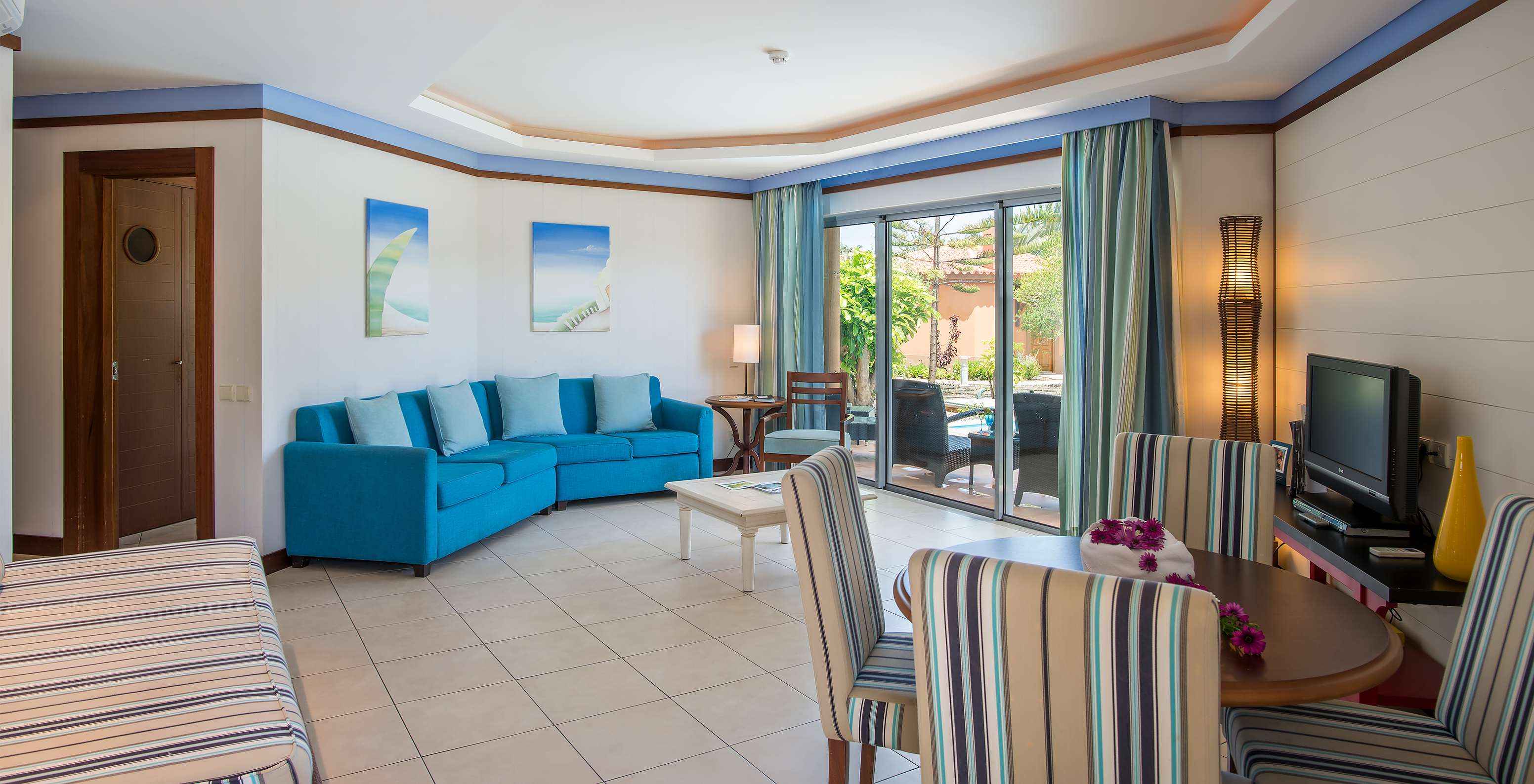 A Pool Villa do Pestana Porto Santo All Inclusive tem uma sala com janela, mesa e cadeiras, sofá e uma televisão
