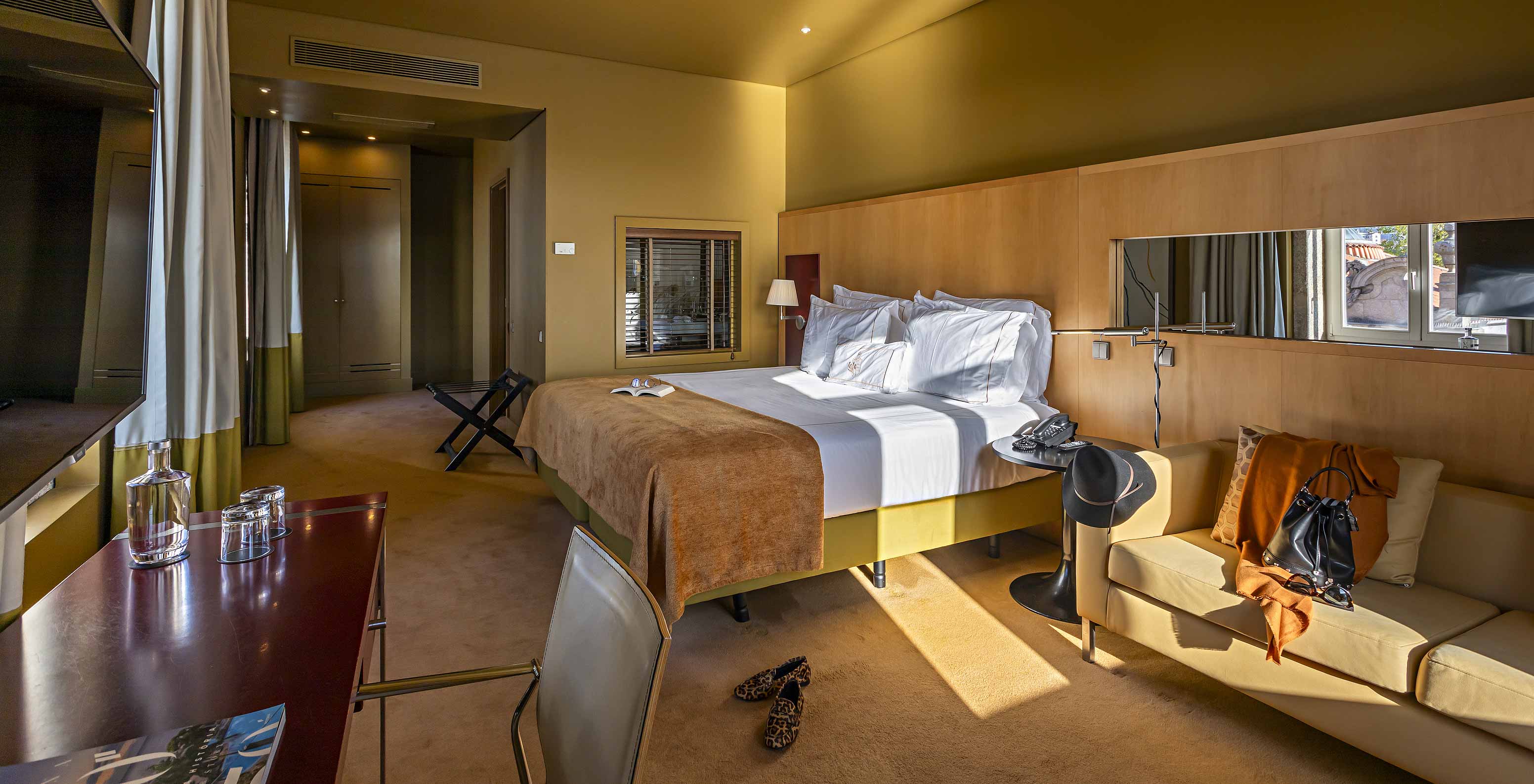 O Deluxe Grand View do Pestana Palácio do Freixo tem uma cama de casal com uma manta camel, um sofá e uma secretária