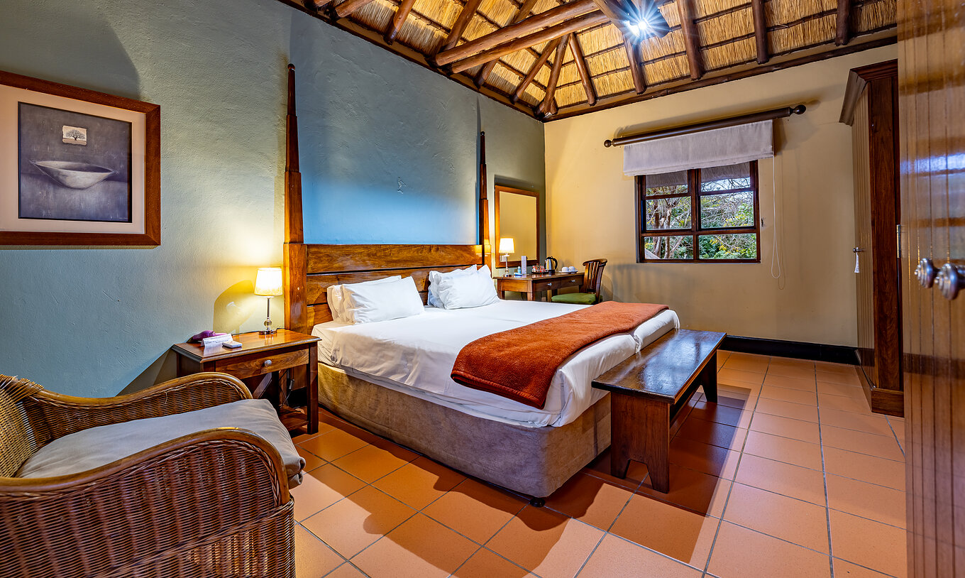 O Quarto Clássico do Pestana Kruger Lodge tem duas camas individuais, uma cadeira e tem uma decoração com madeira