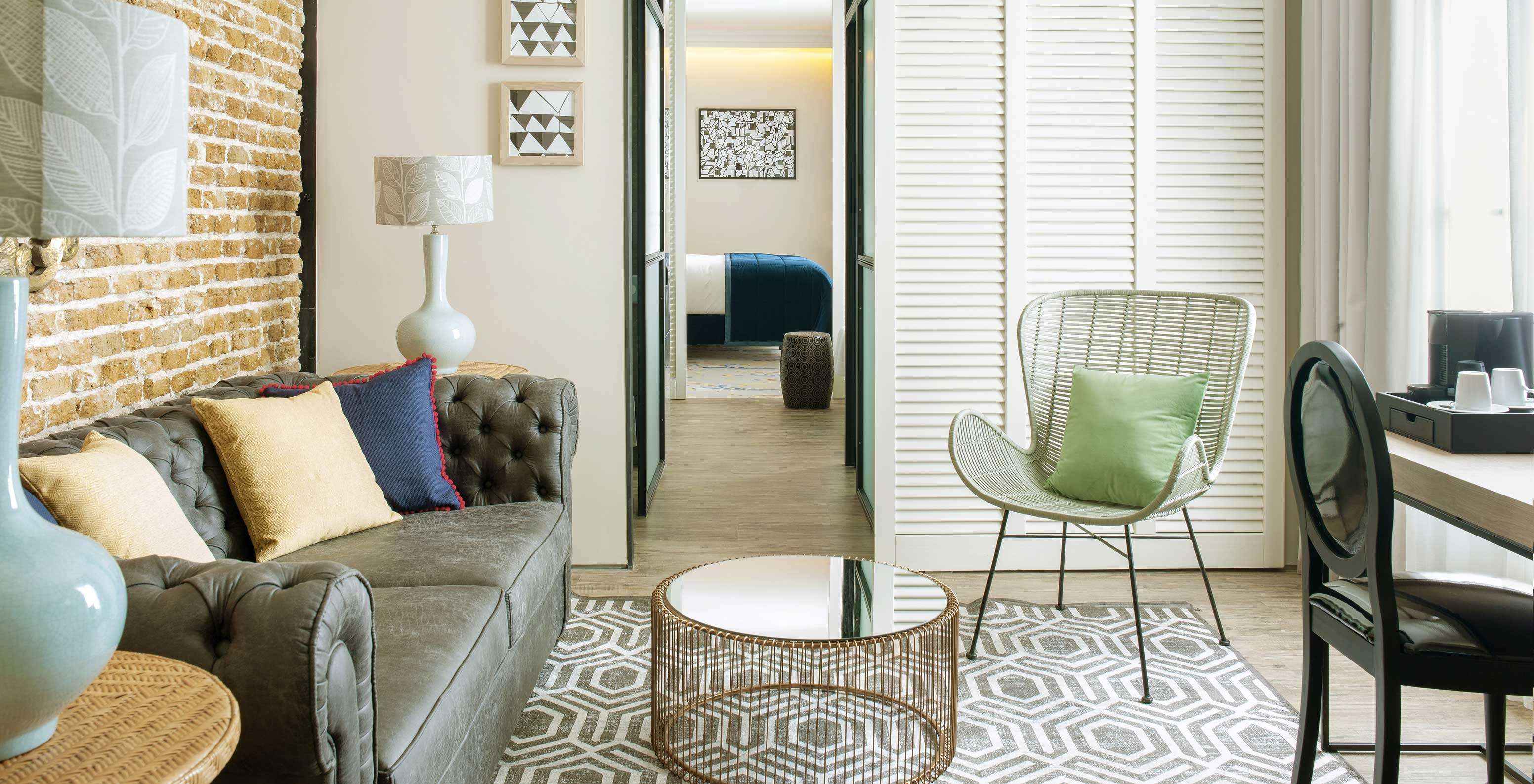 A Suite do Pestana Plaza Mayor tem uma sala de estar independente com sofá, mesas de apoio com candeeiros e máquina de café