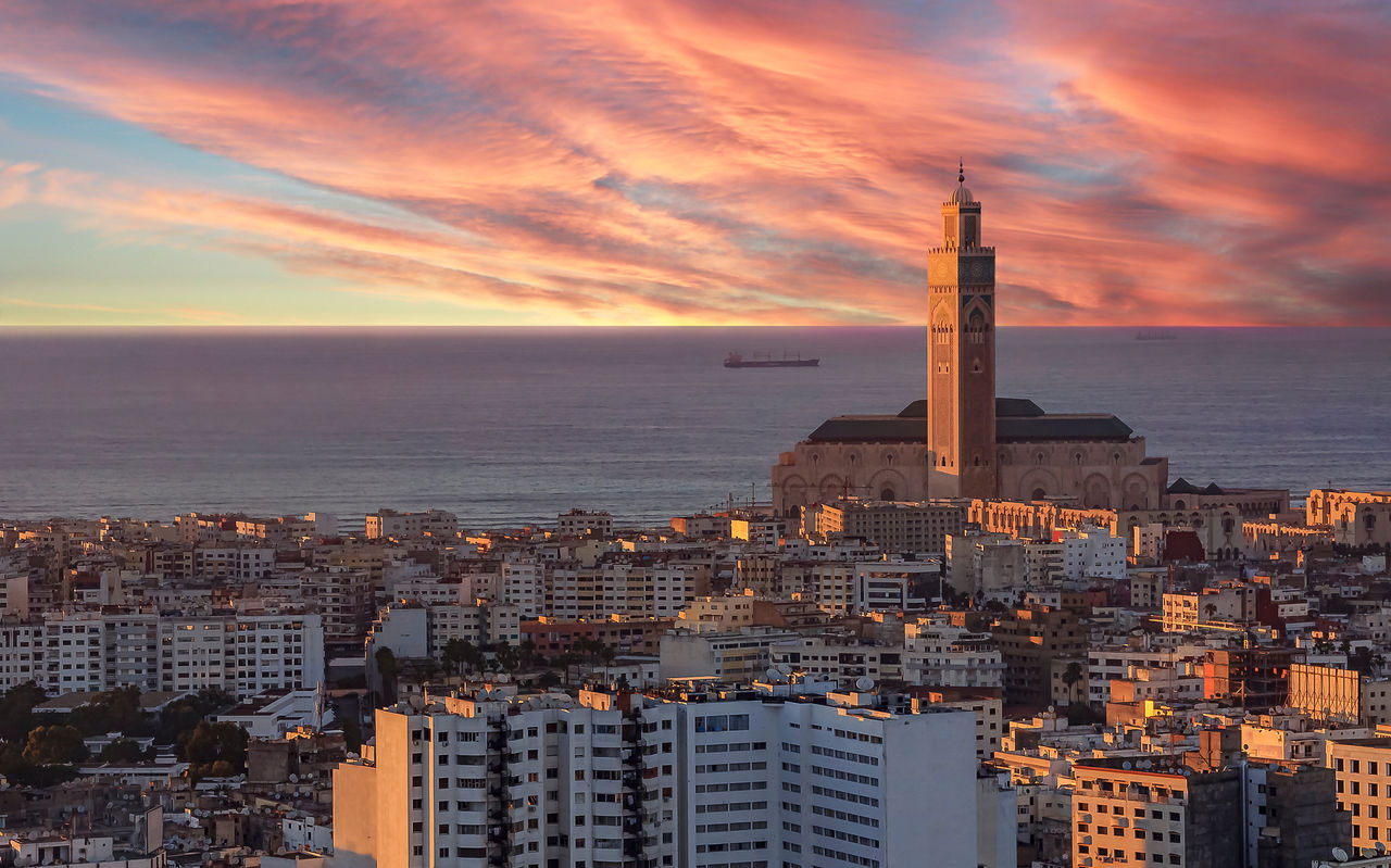 Luchtfoto van Casablanca, zonsondergang verlicht gebouwen, lucht aan de horizon, zee en toren