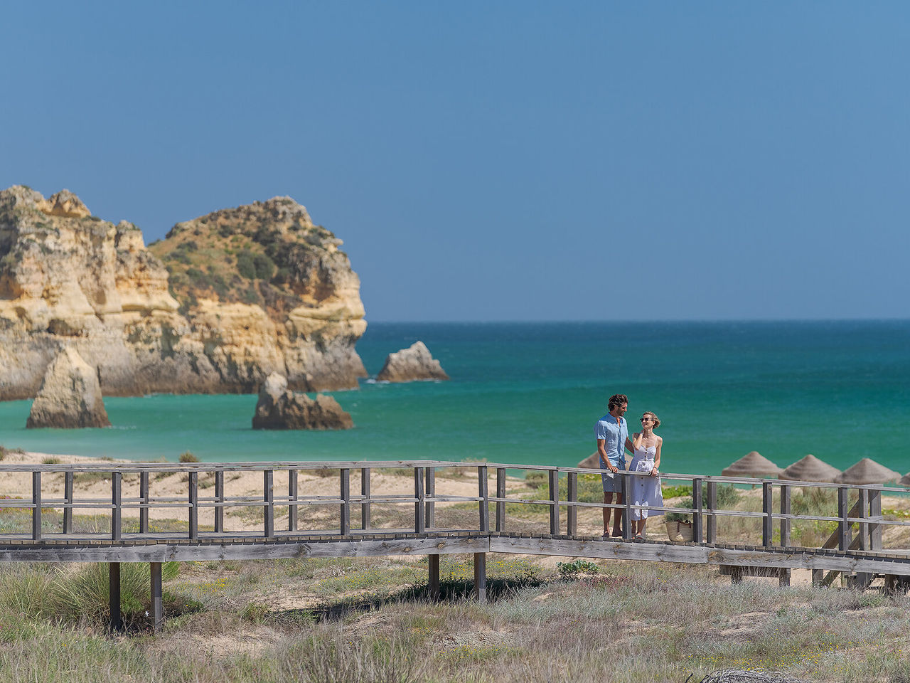 Paar bewondert het uitzicht op een strand in Alvor, Algarve, terwijl ze langs de loopbruggen bij de zee wandelen