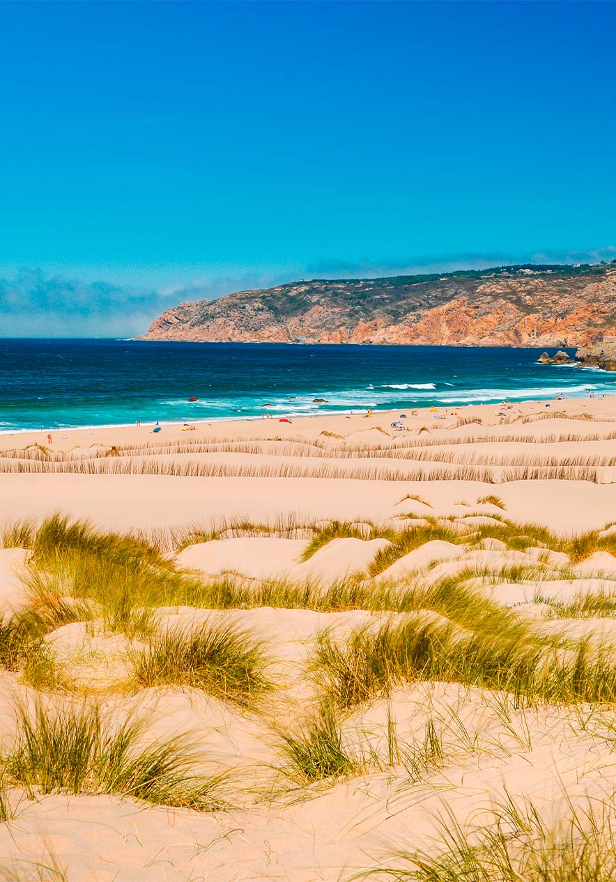 Het strand van Guincho in Cascais, met een uitgestrekt zandstrand, duinen en blauw water