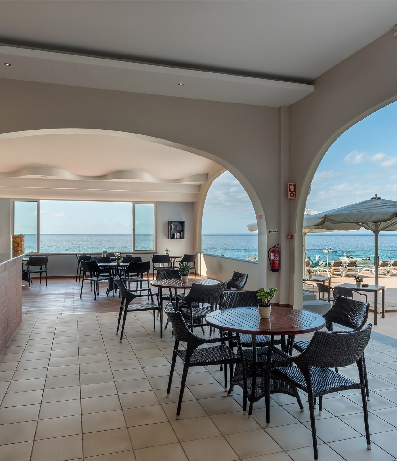 De bar Atlântico, van het 5-sterrenhotel op Madeira, heeft een overdekte veranda met stoelen en tafels, met uitzicht op zee