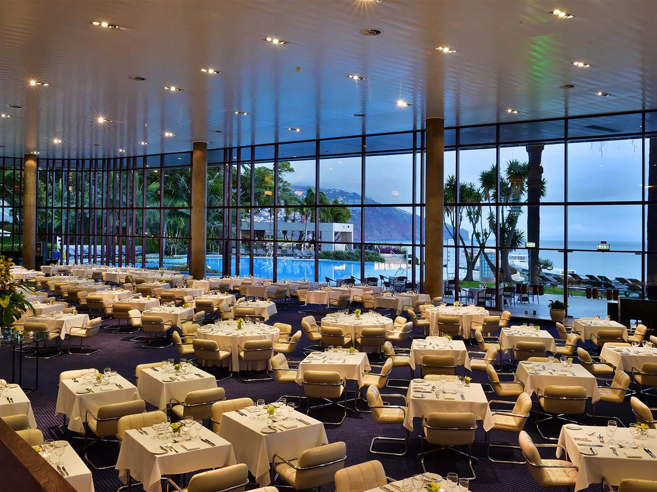 Het restaurant Panorâmico, van het 5-sterrenhotel in het centrum van Funchal, heeft verschillende tafels met beige kussens