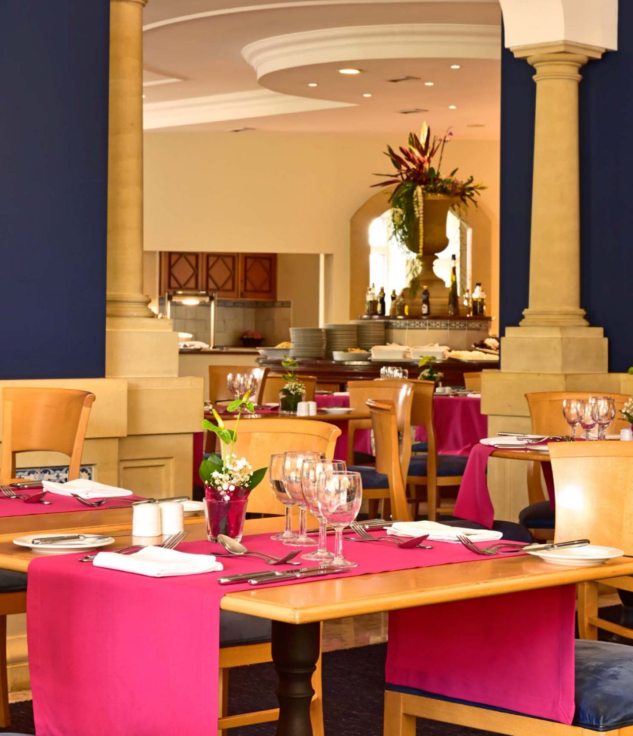 Het restaurant A Vila, van het Hotel de Charme op Madeira heeft verschillende tafels, met een rood tafelkleed en bloemen