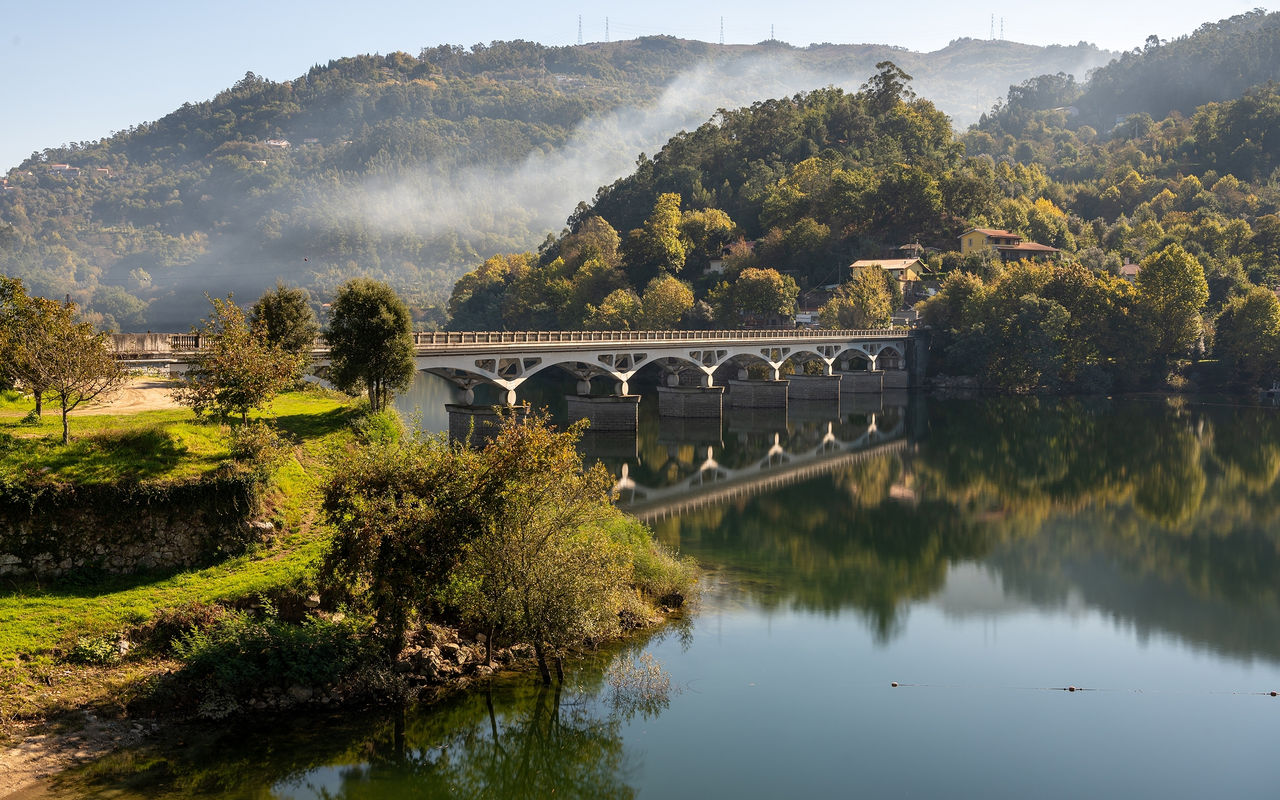 Landschap in het noorden van Portugal met een stenen brug over een rivier, omgeven door groene heuvels