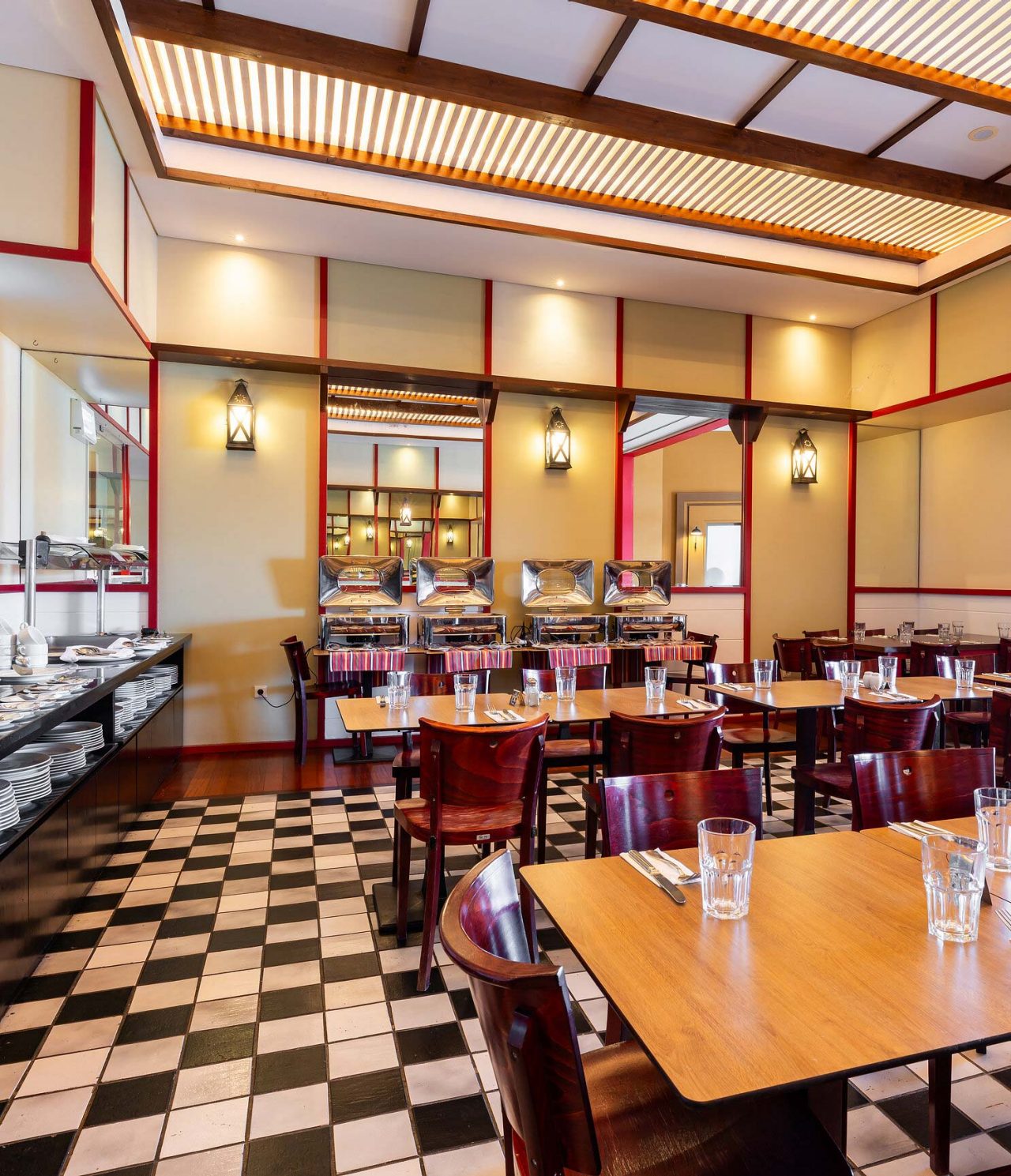 Restaurant Luigi van het 5-sterrenresort op Porto Santo heeft een vloer met zwarte en witte tegels en donkere stoelen.