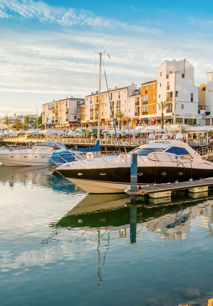 Vilamoura marina in the Algarve at sunset with anchored boats of various sizes and styles and calm water
