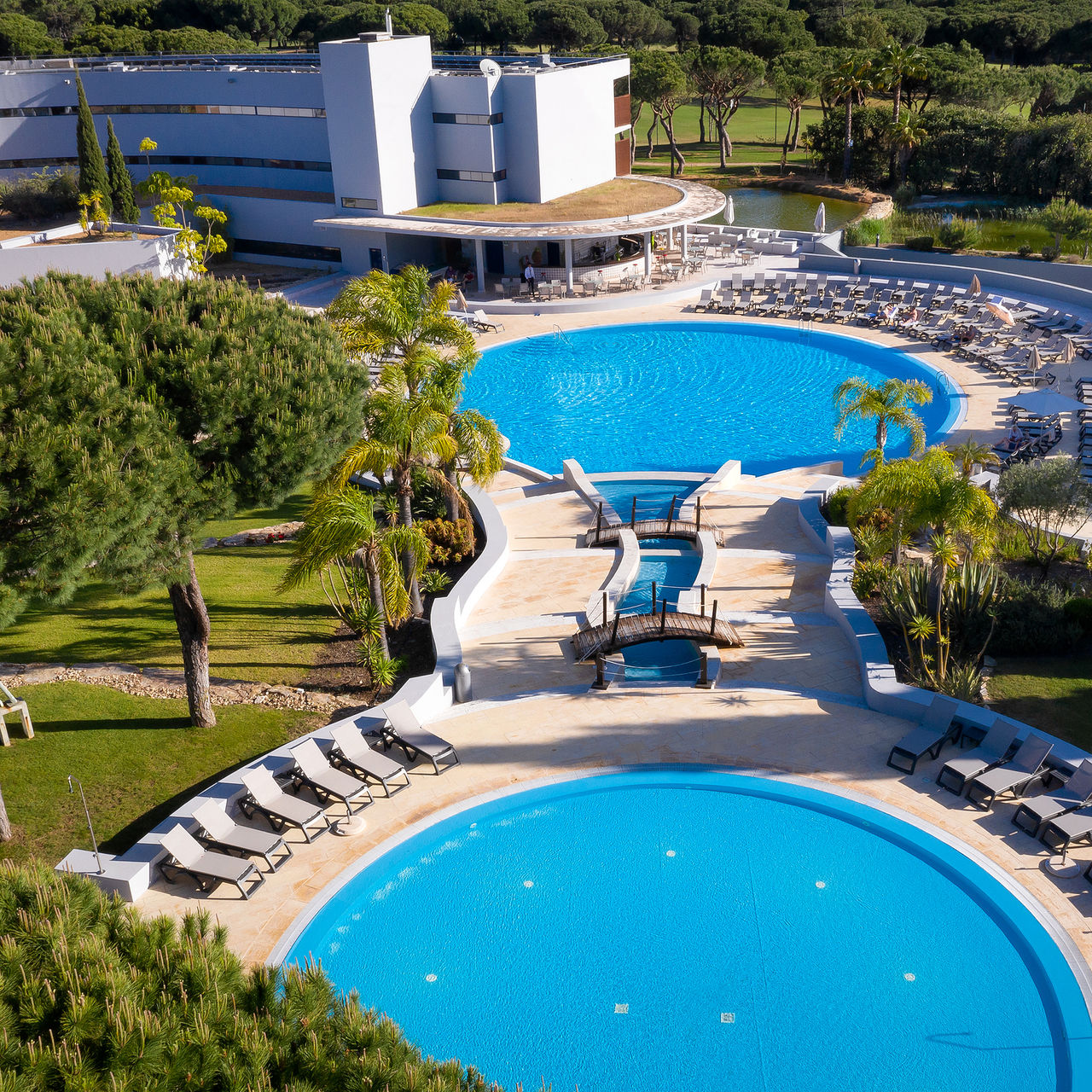 Outdoor pools at Pestana Vila Sol, a 5-star hotel in Vilamoura, with sun loungers around inviting relaxation