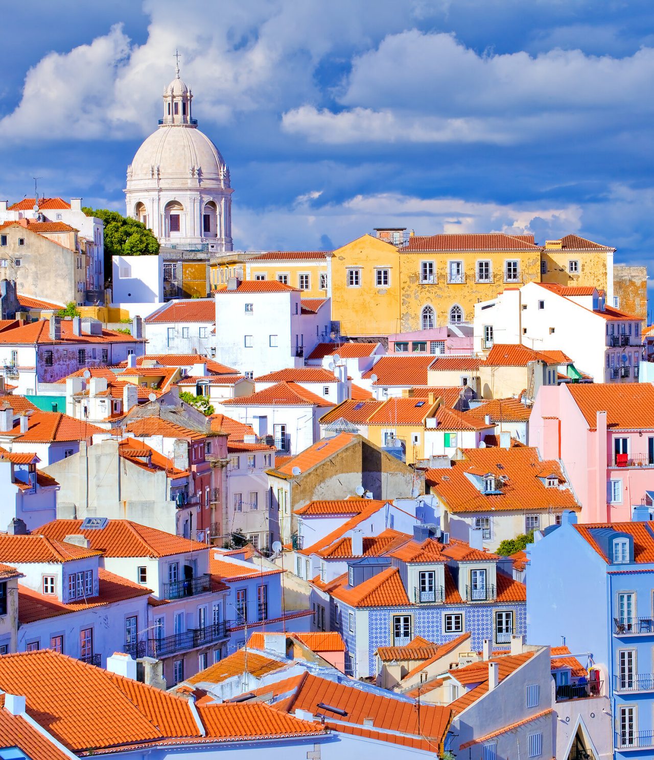 Historic center of Lisbon, with typical buildings, brick roofs, and a basilica in the background