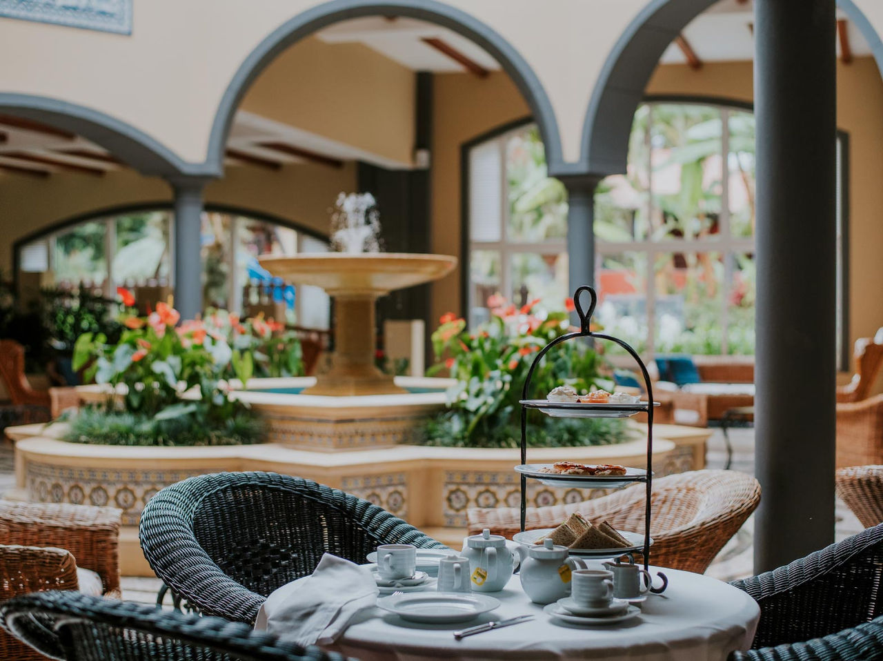 The bar A Fonte, at the Hotel de Charme in Madeira has a fountain with water and flowers and a table with chairs