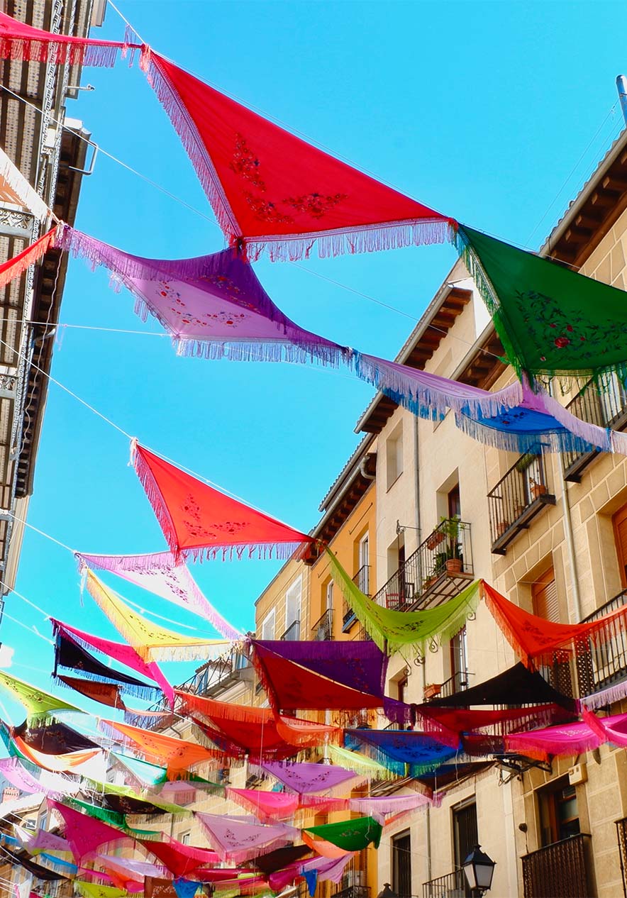 Street with shawls and colorful threads hanging from the windows and balconies of buildings on the sides of the street