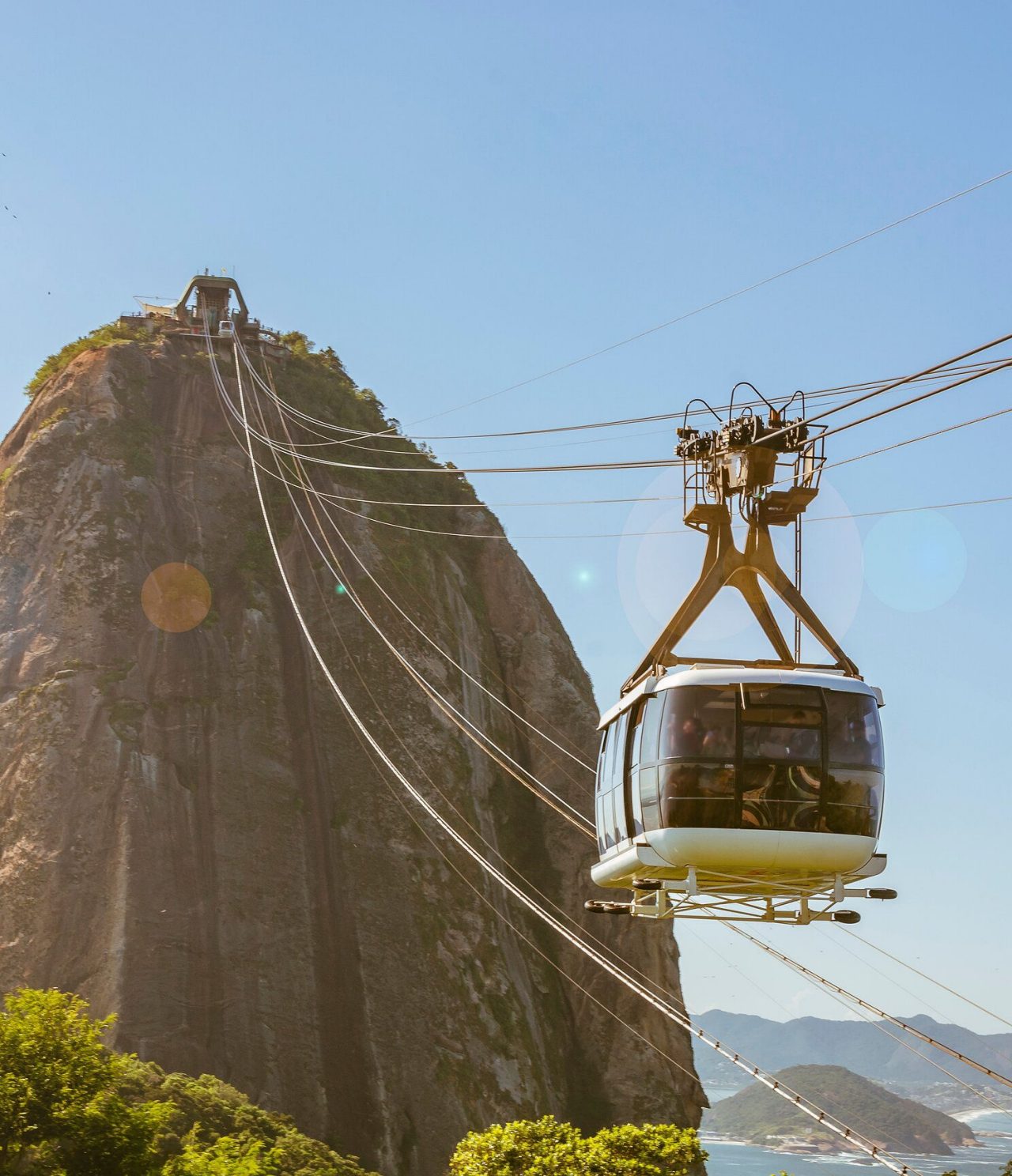 View of the cable car in Rio de Janeiro, heading towards a high hill, with the sea in the background